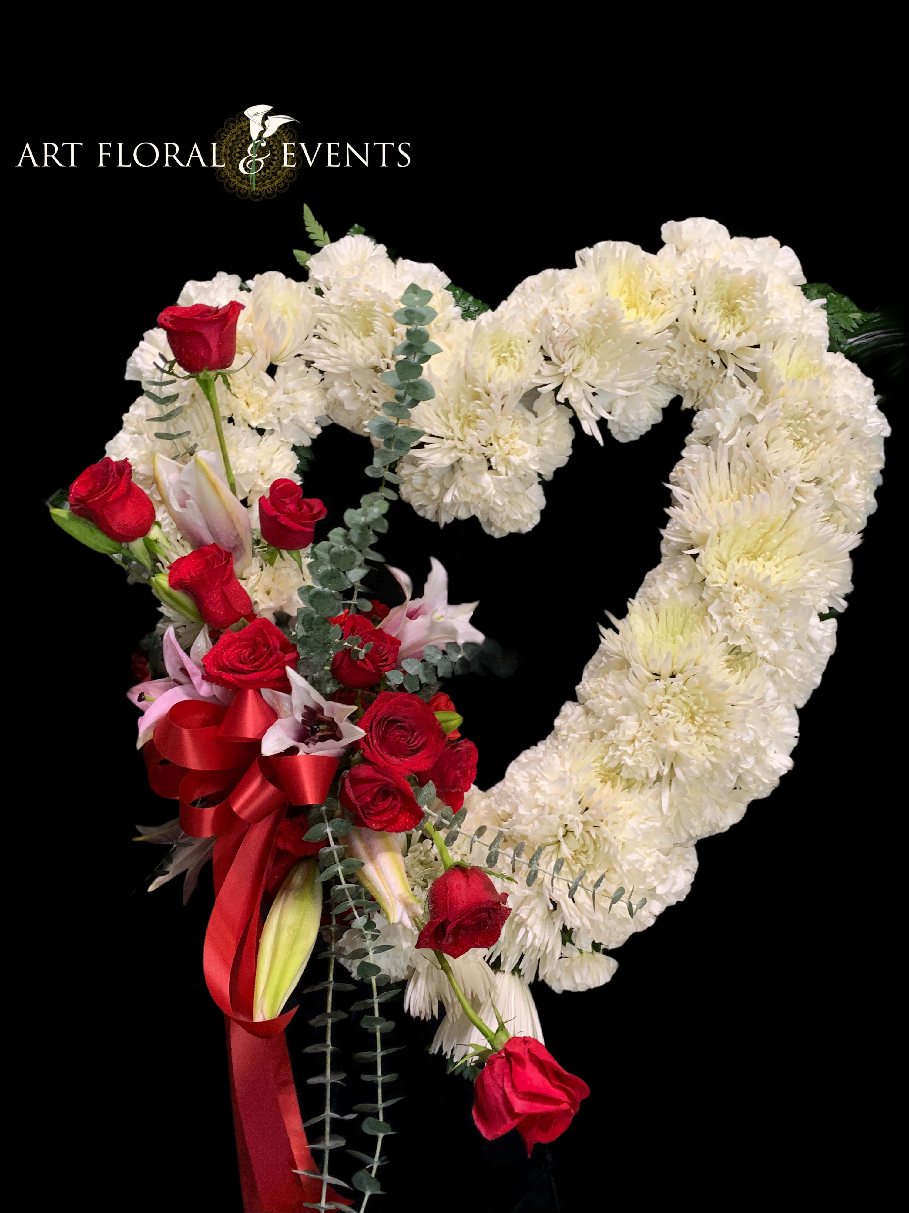 Heart-shaped floral arrangement with white blooms and red roses on a black background