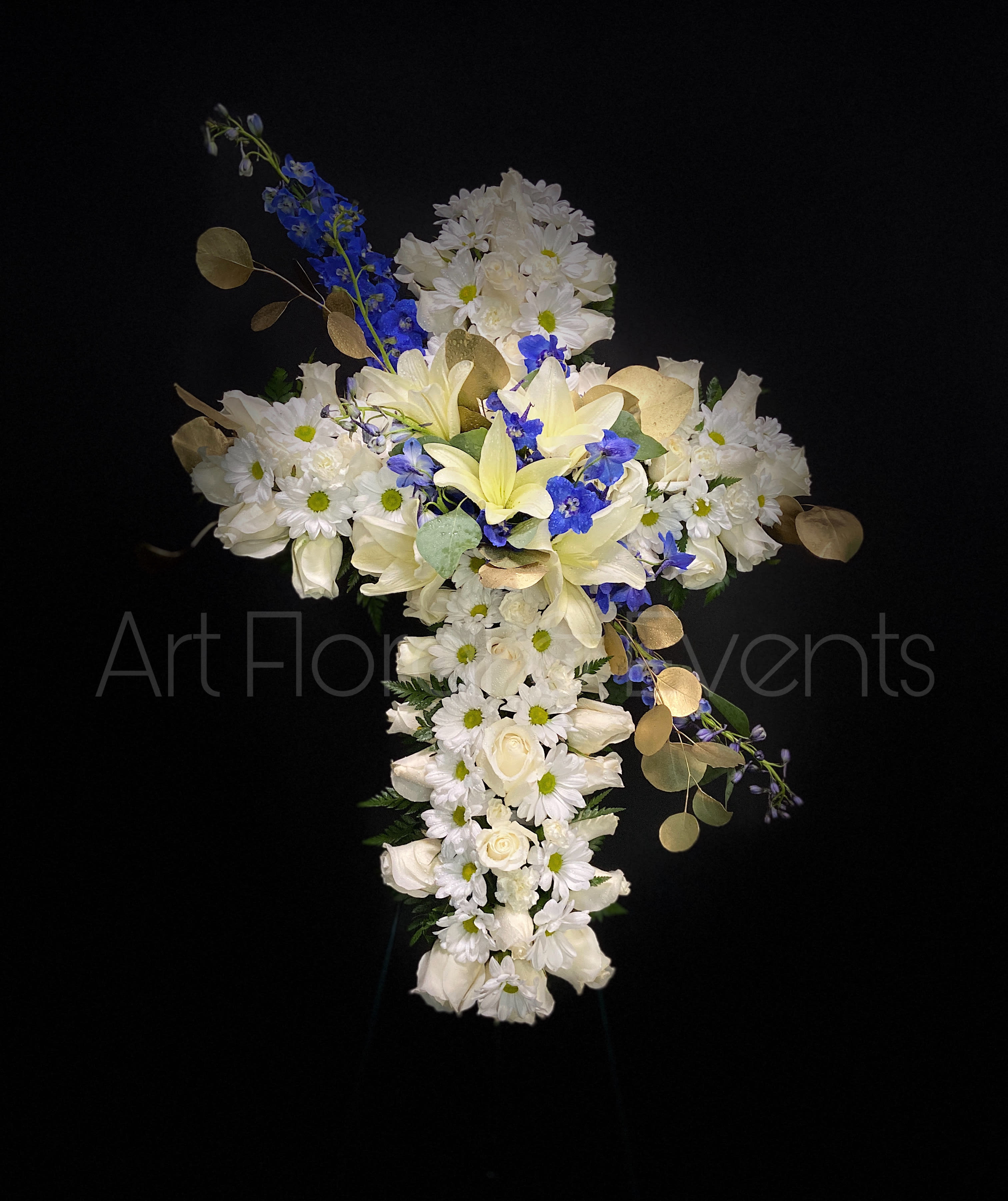 Cross-shaped floral arrangement with white flowers and blue accents