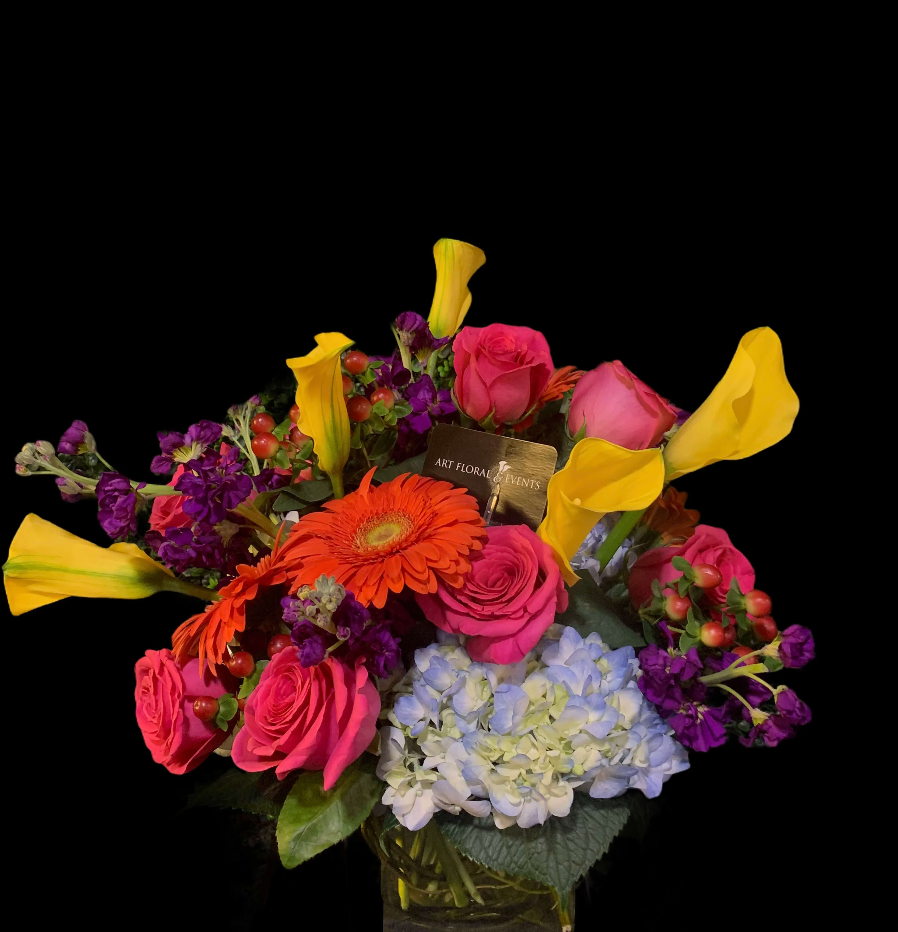 Colorful bouquet with pink roses, yellow calla lilies, and blue hydrangea in a vase
