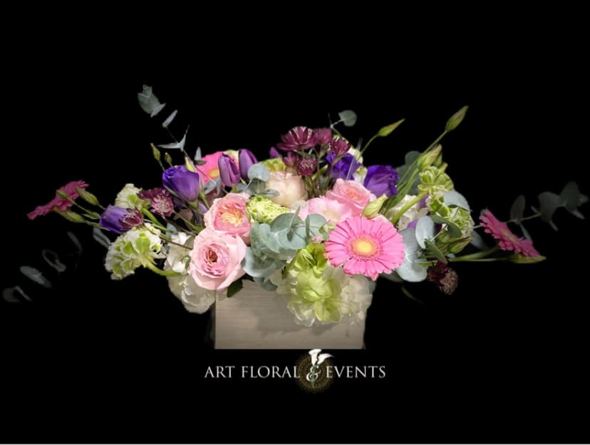 Mixed pink, purple, and green floral arrangement in a square box
