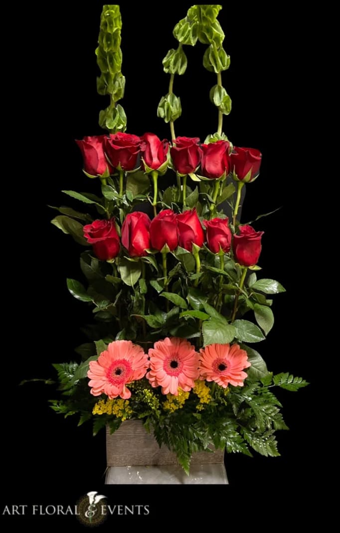 Tall arrangement of red roses and pink gerbera daisies in a square vase