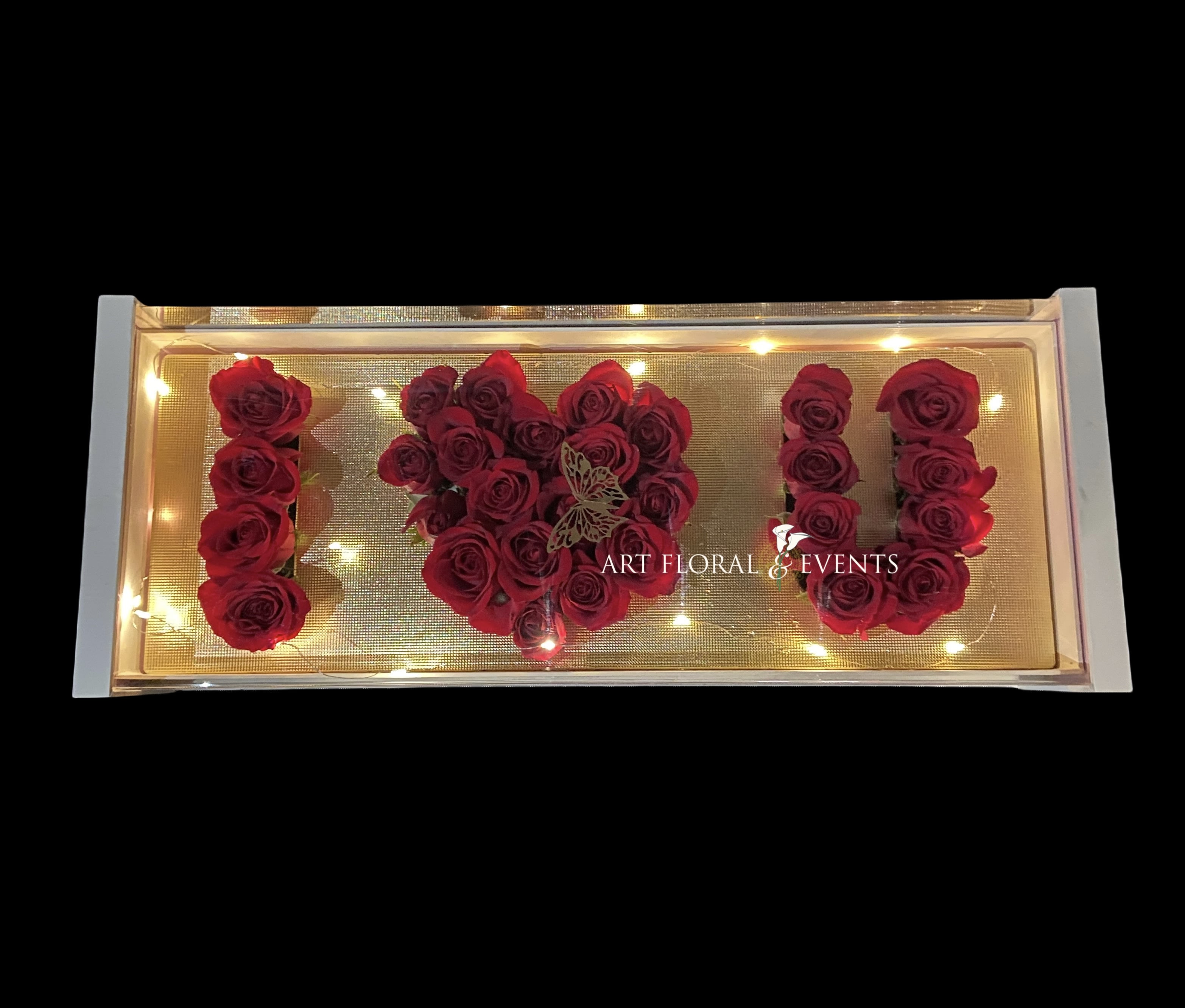 Red roses arranged to spell "I U" in a lit display box