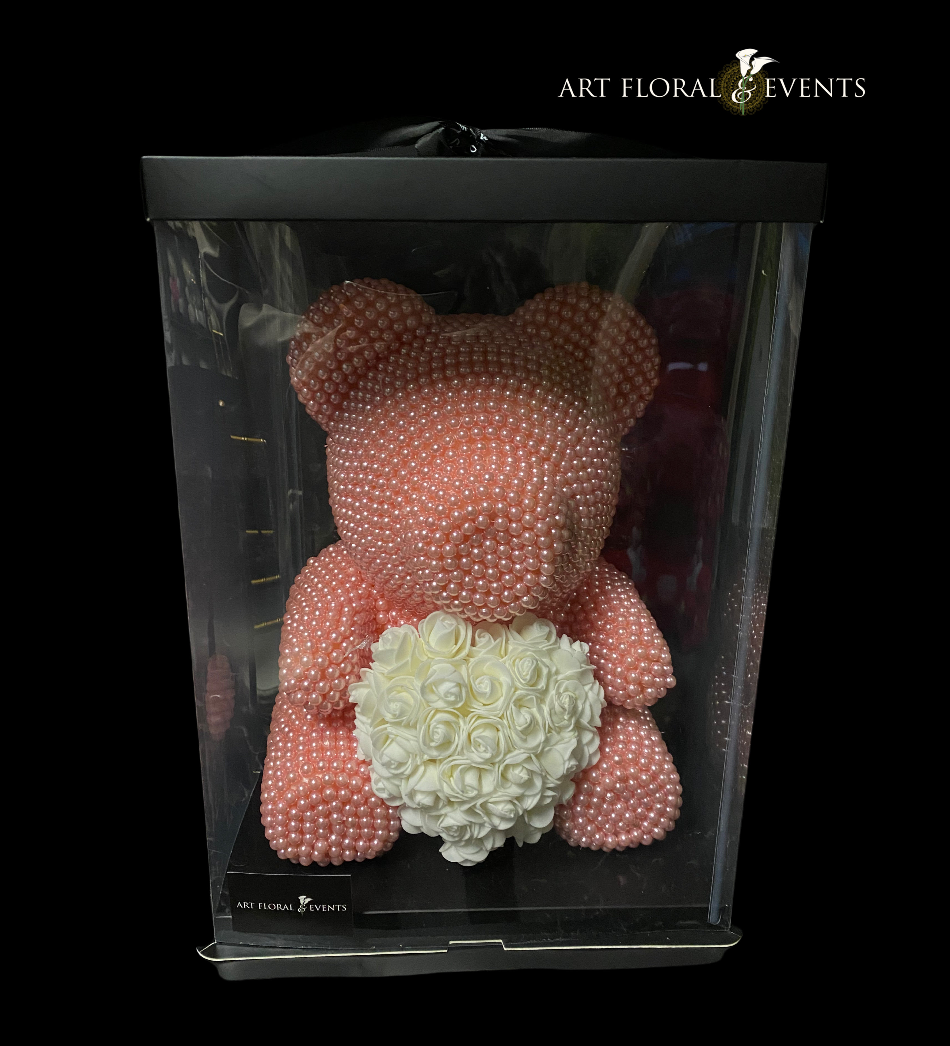 Pink pearl teddy bear holding a white rose heart in a display box