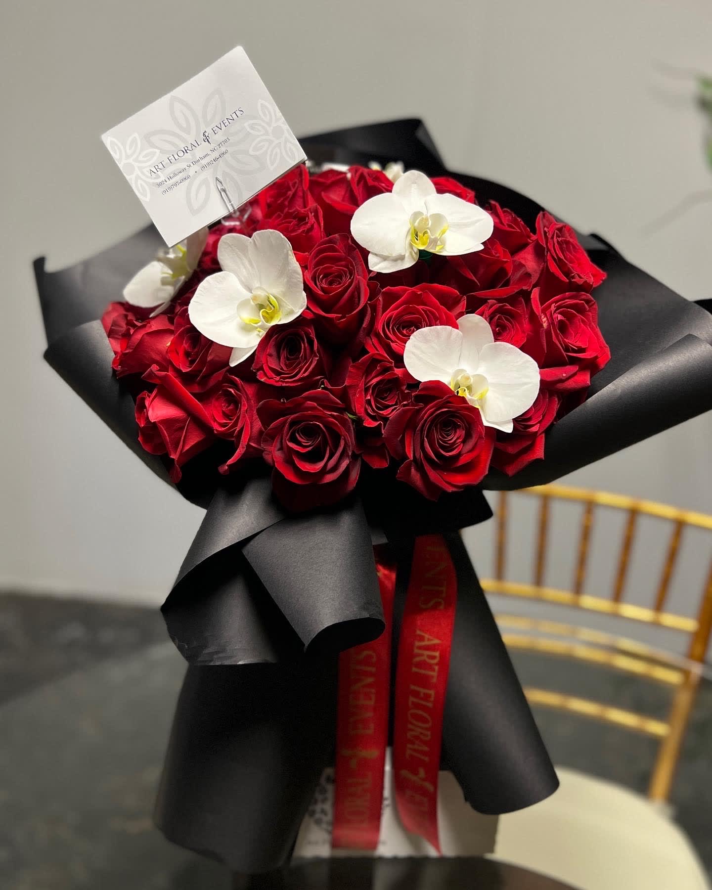 Bouquet of red roses with white orchids wrapped in black paper