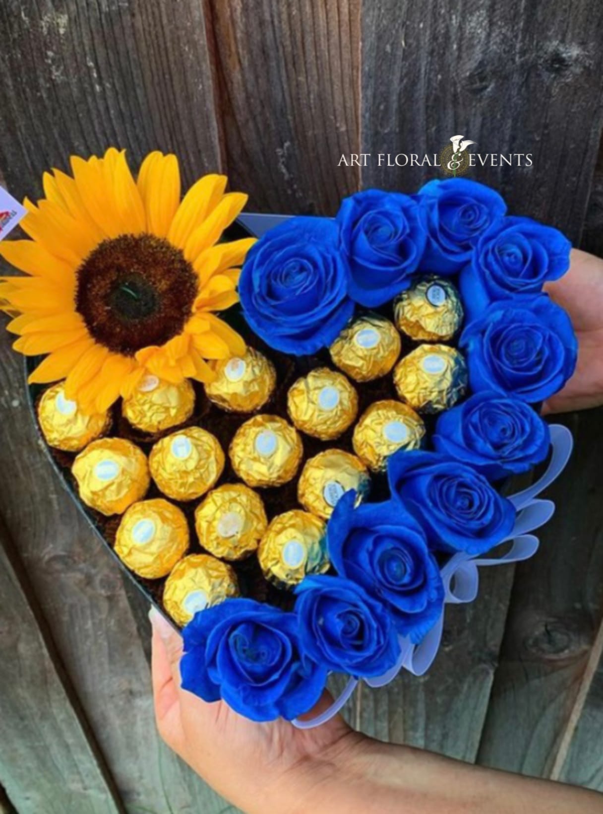 Heart-shaped bouquet with a sunflower, blue roses, and gold-wrapped chocolates
