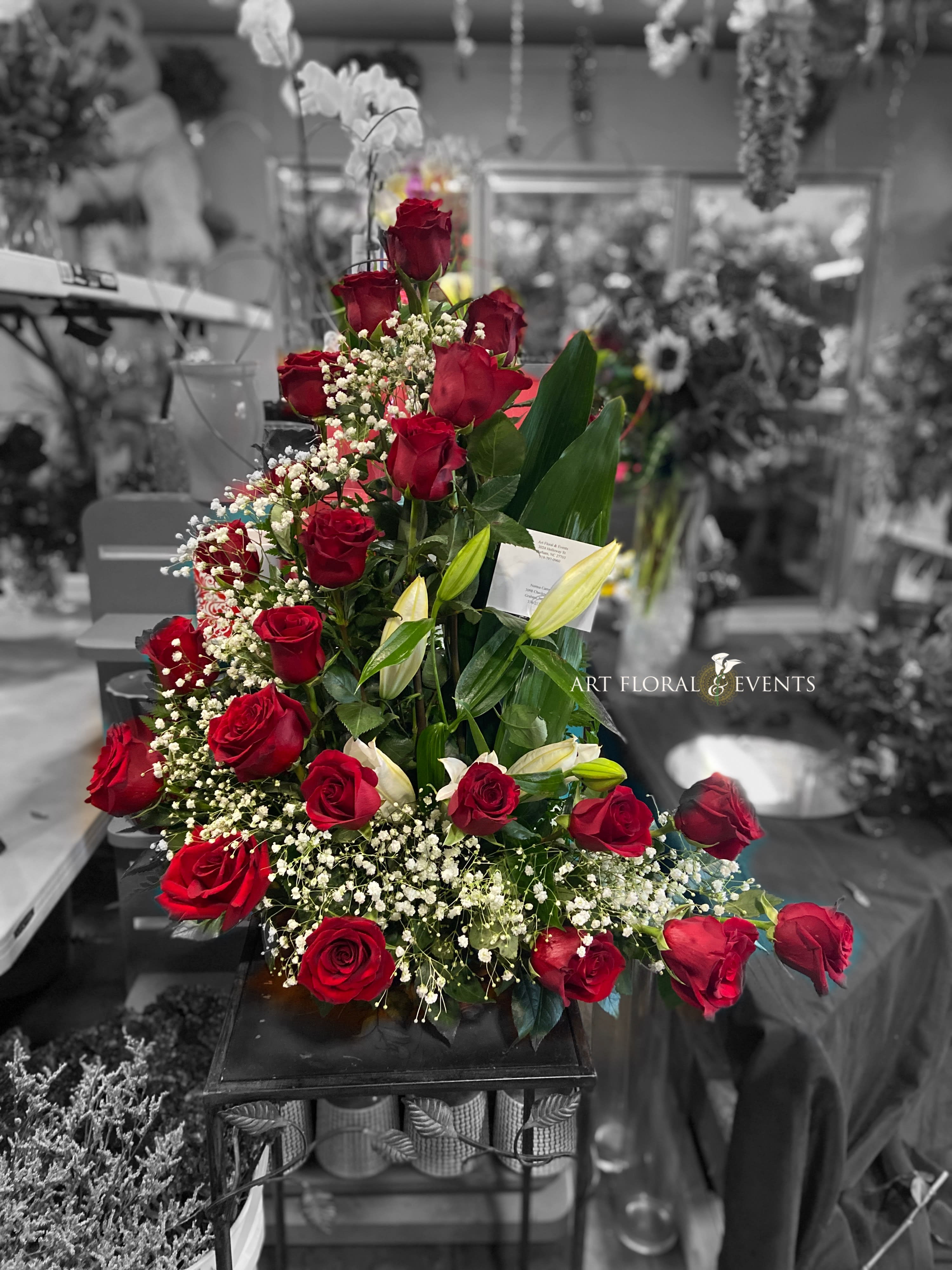 Tall arrangement of red roses with white baby's breath and lilies