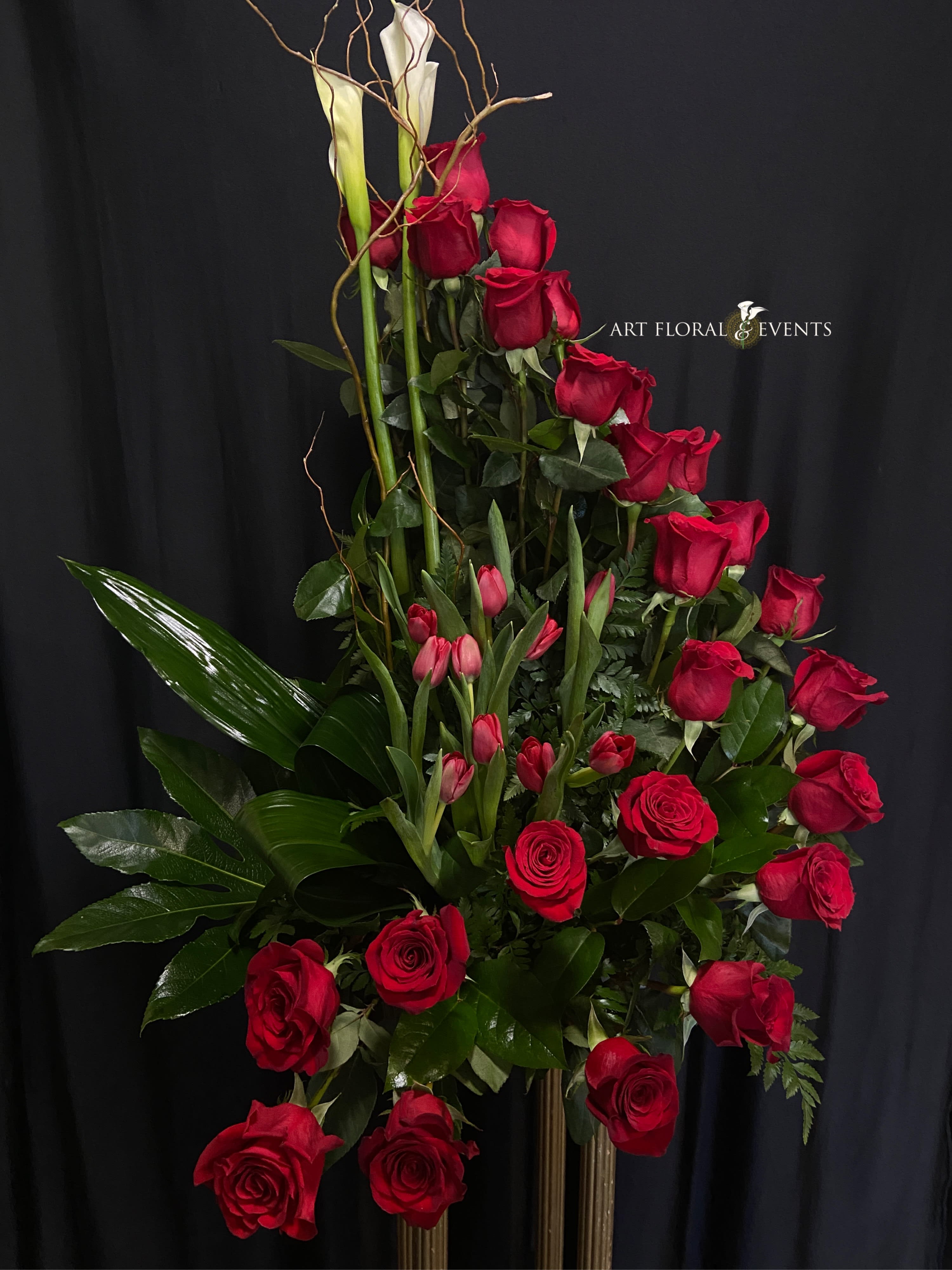 Tall arrangement of red roses and pink tulips with white calla lilies
