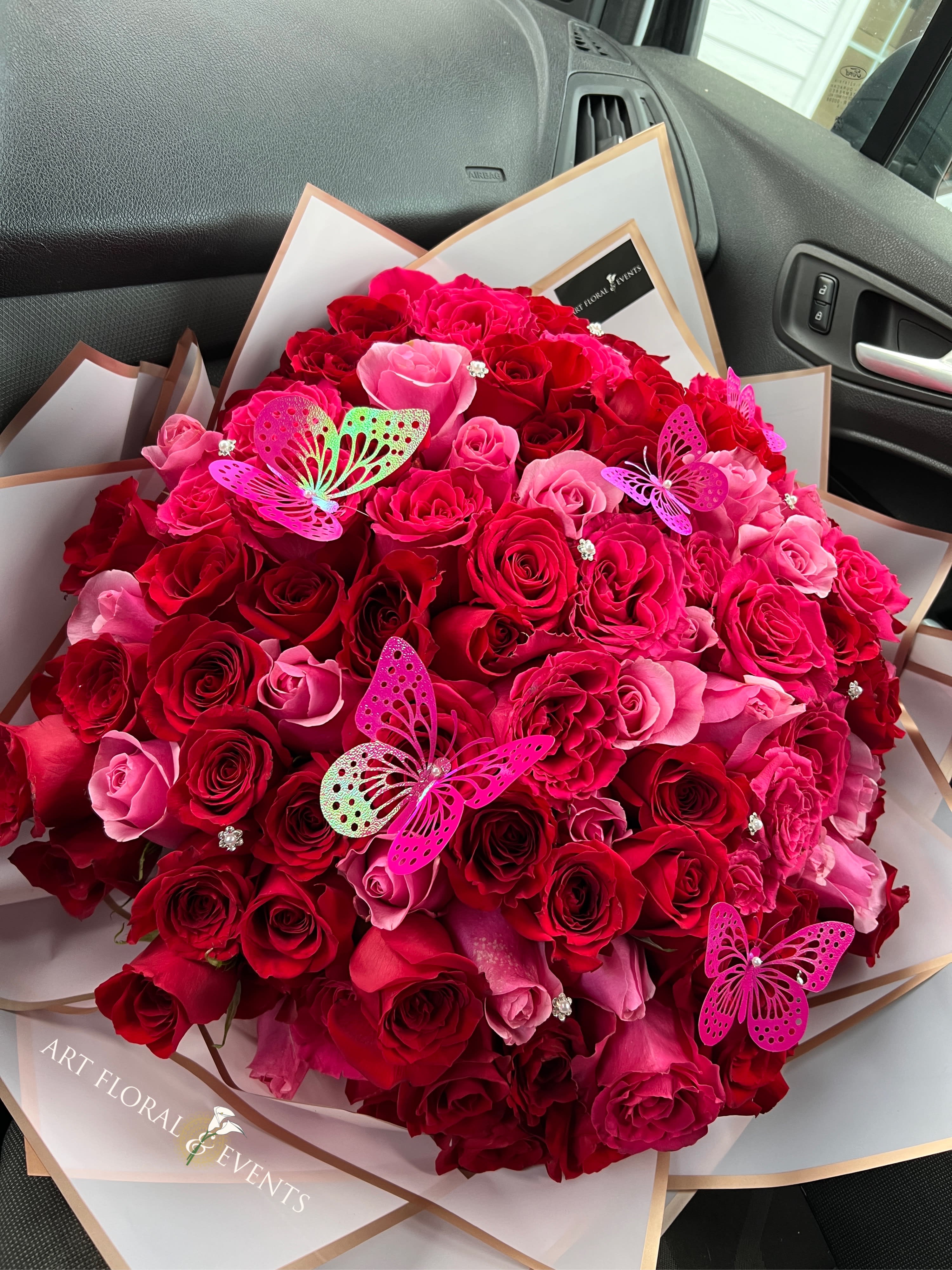 Large bouquet of red and pink roses with butterfly decorations