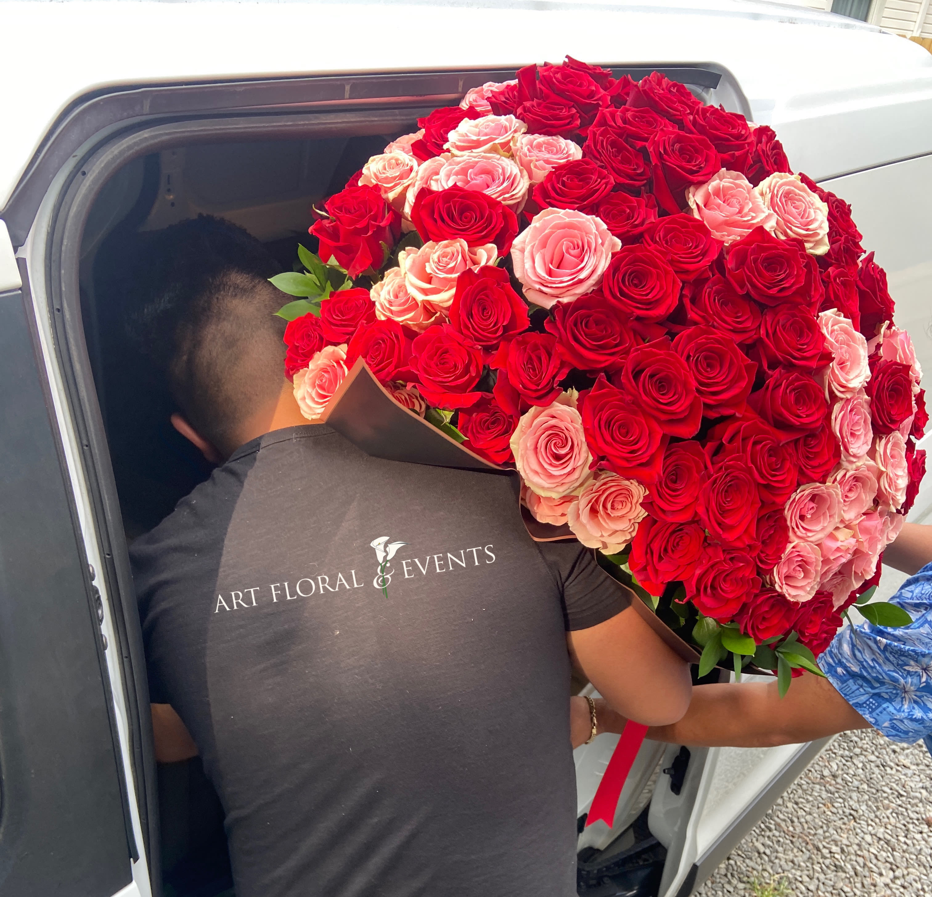Large bouquet of red and pink roses being carried into a car