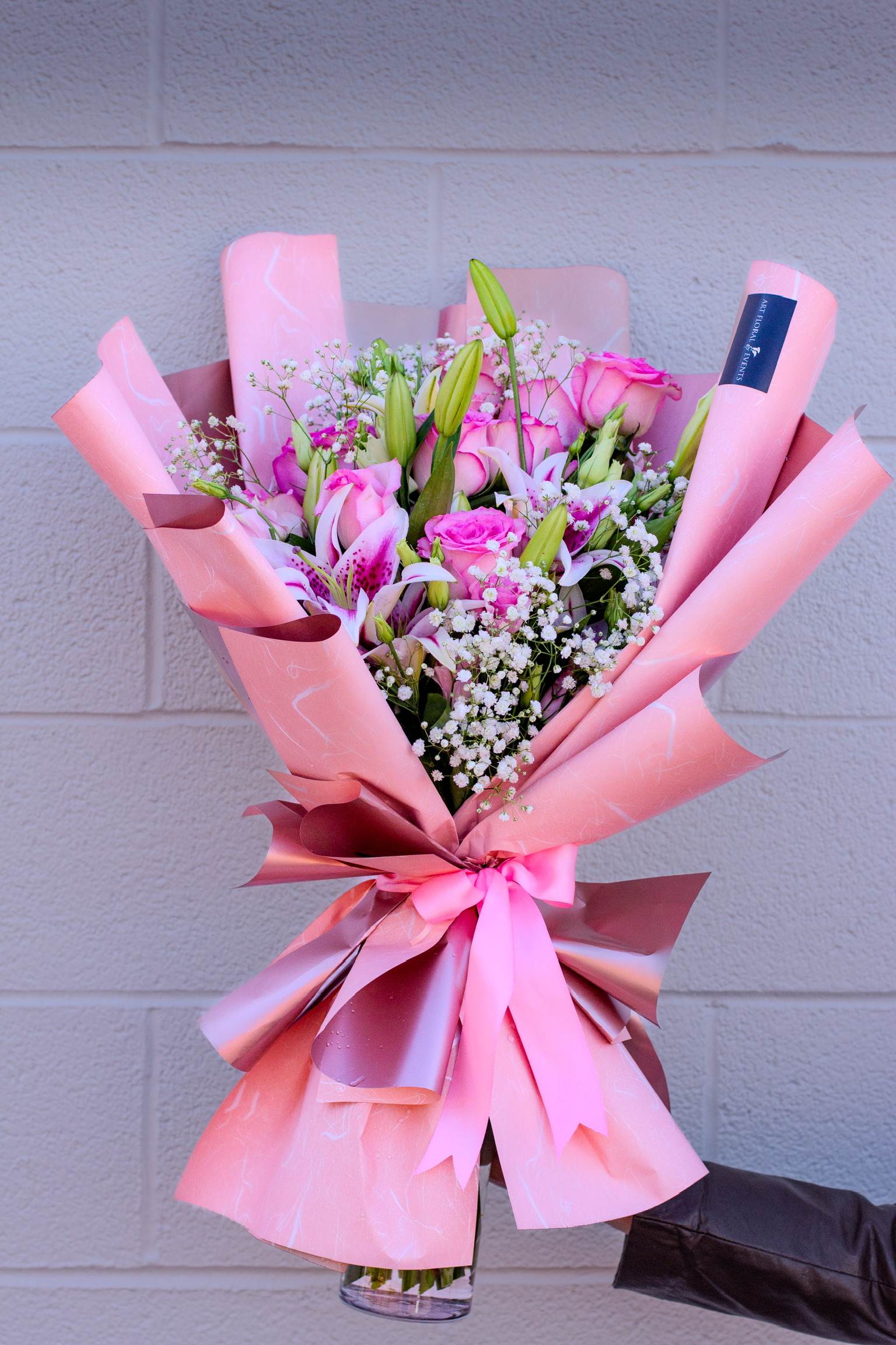 Pink bouquet of roses and lilies wrapped in pink paper