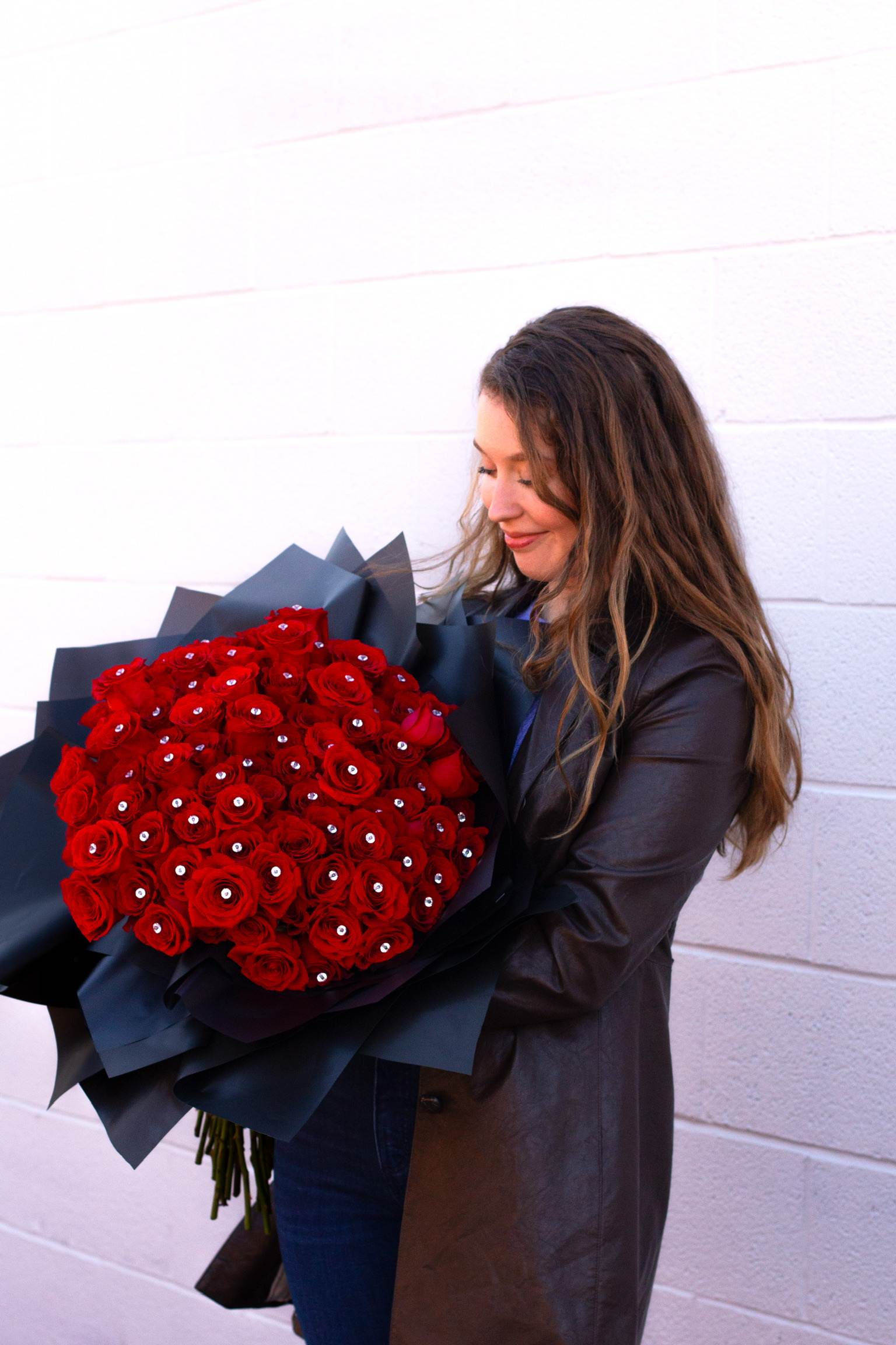 Woman holding a large bouquet of red roses wrapped in black paper