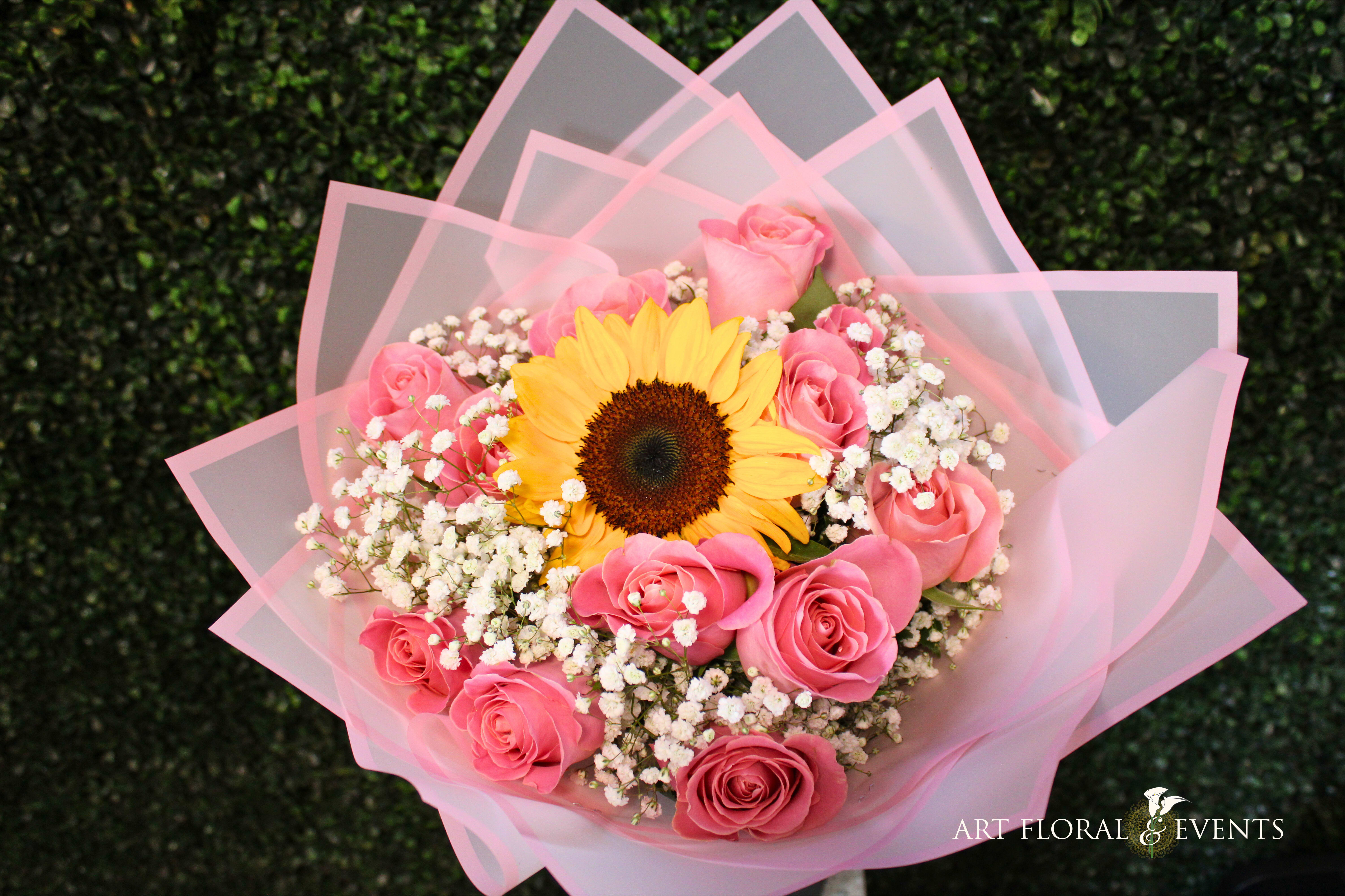 Pink rose bouquet with a sunflower and baby's breath wrapped in pink paper
