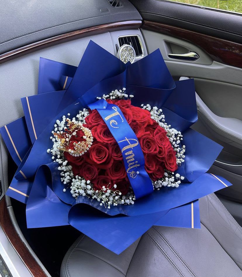 Red rose bouquet wrapped in blue paper with a crown topper