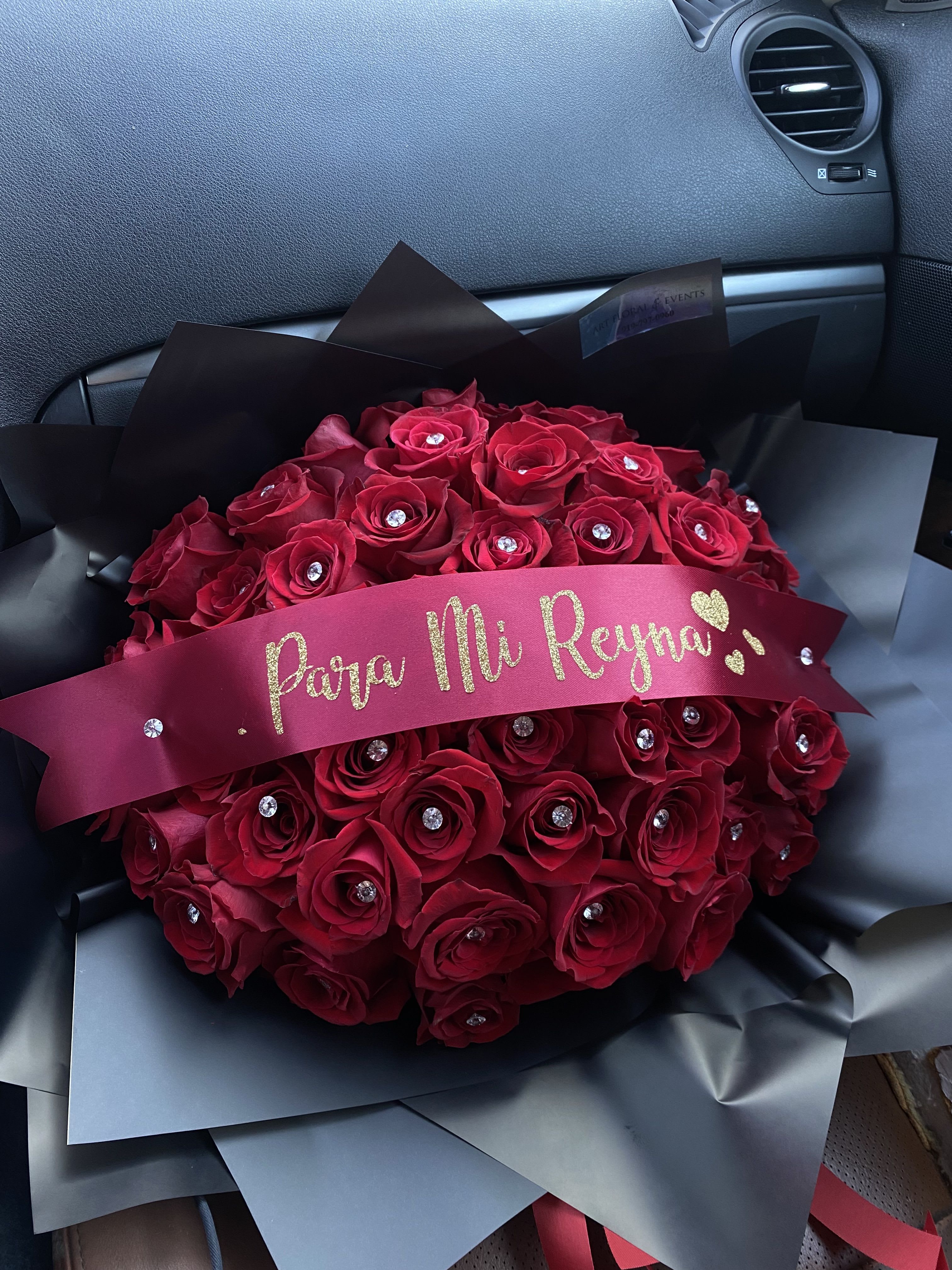 Bouquet of red roses wrapped in black paper with a pink ribbon