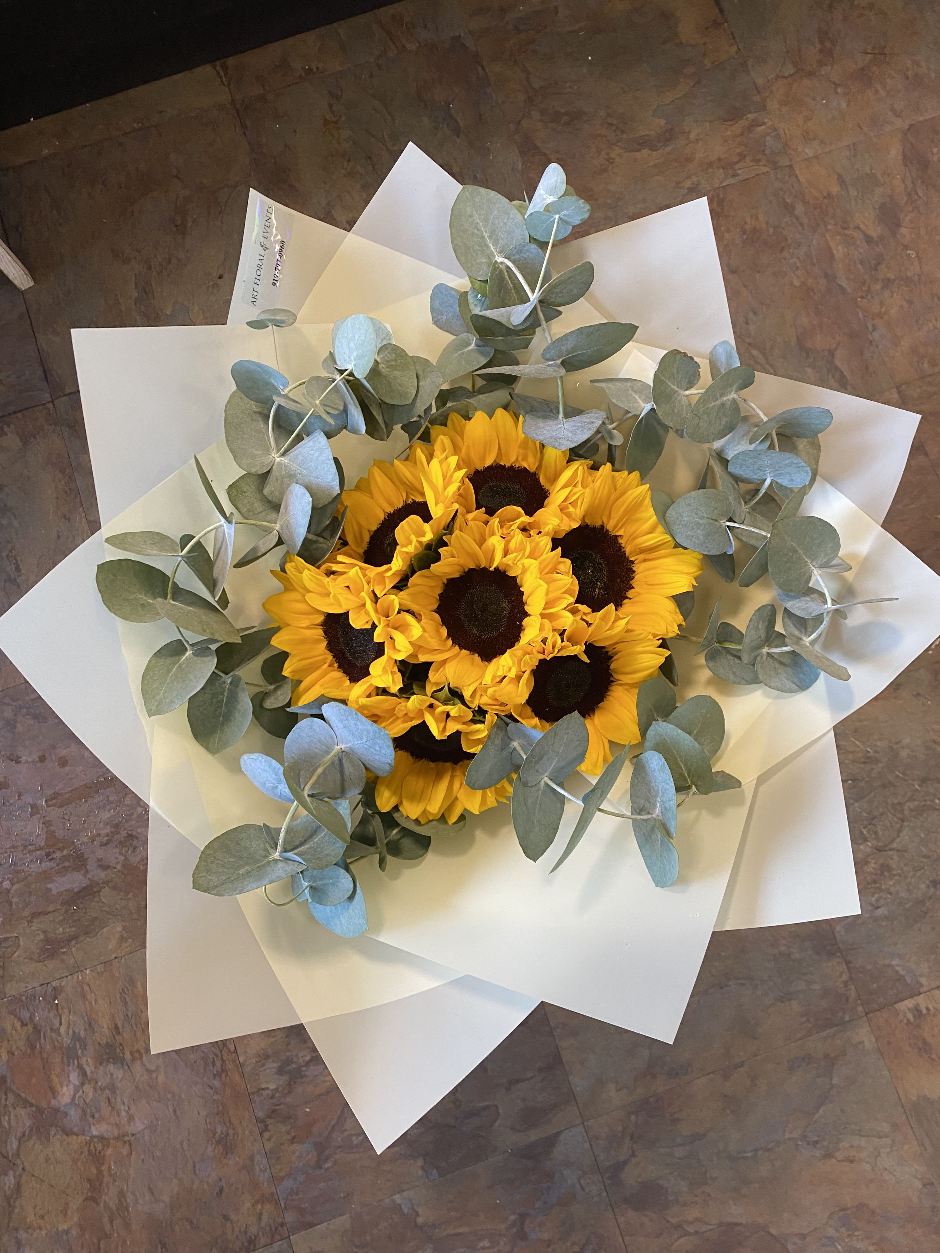 Bouquet of yellow sunflowers wrapped in white paper with eucalyptus