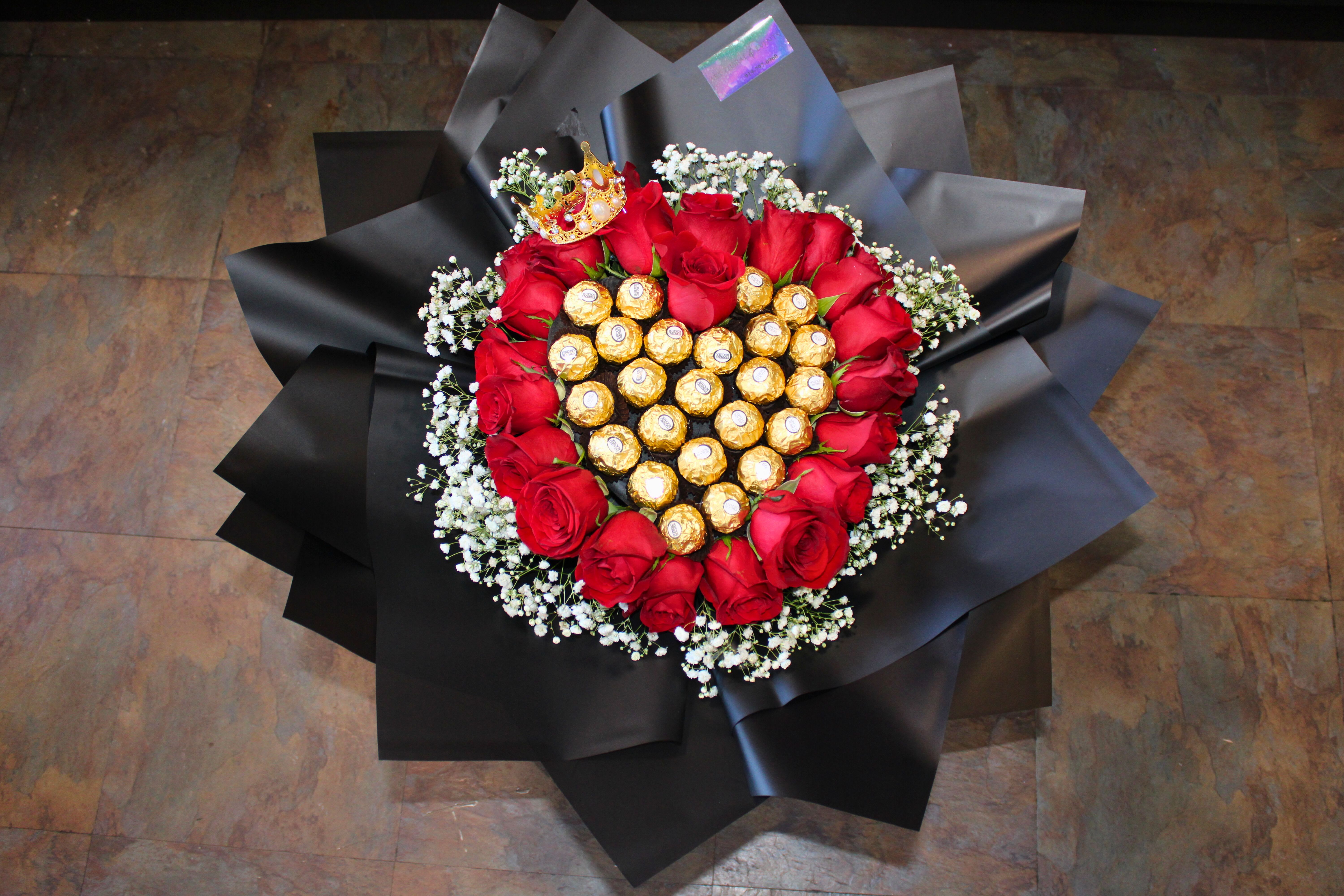 Heart-shaped bouquet of red roses with chocolates in black wrap
