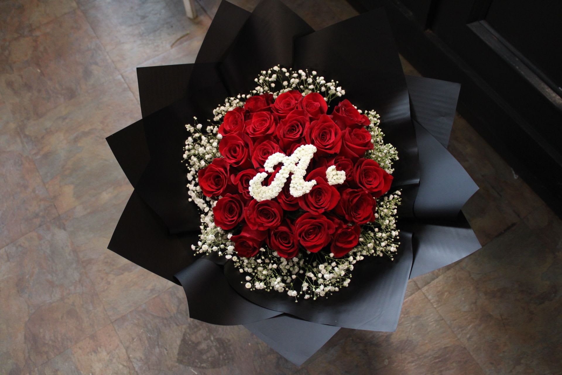 Bouquet of red roses with white baby's breath and a white monogram