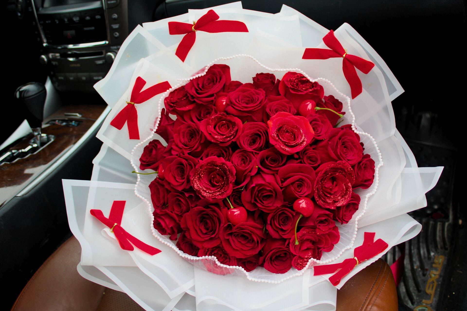Bouquet of red roses wrapped in white paper with red bows