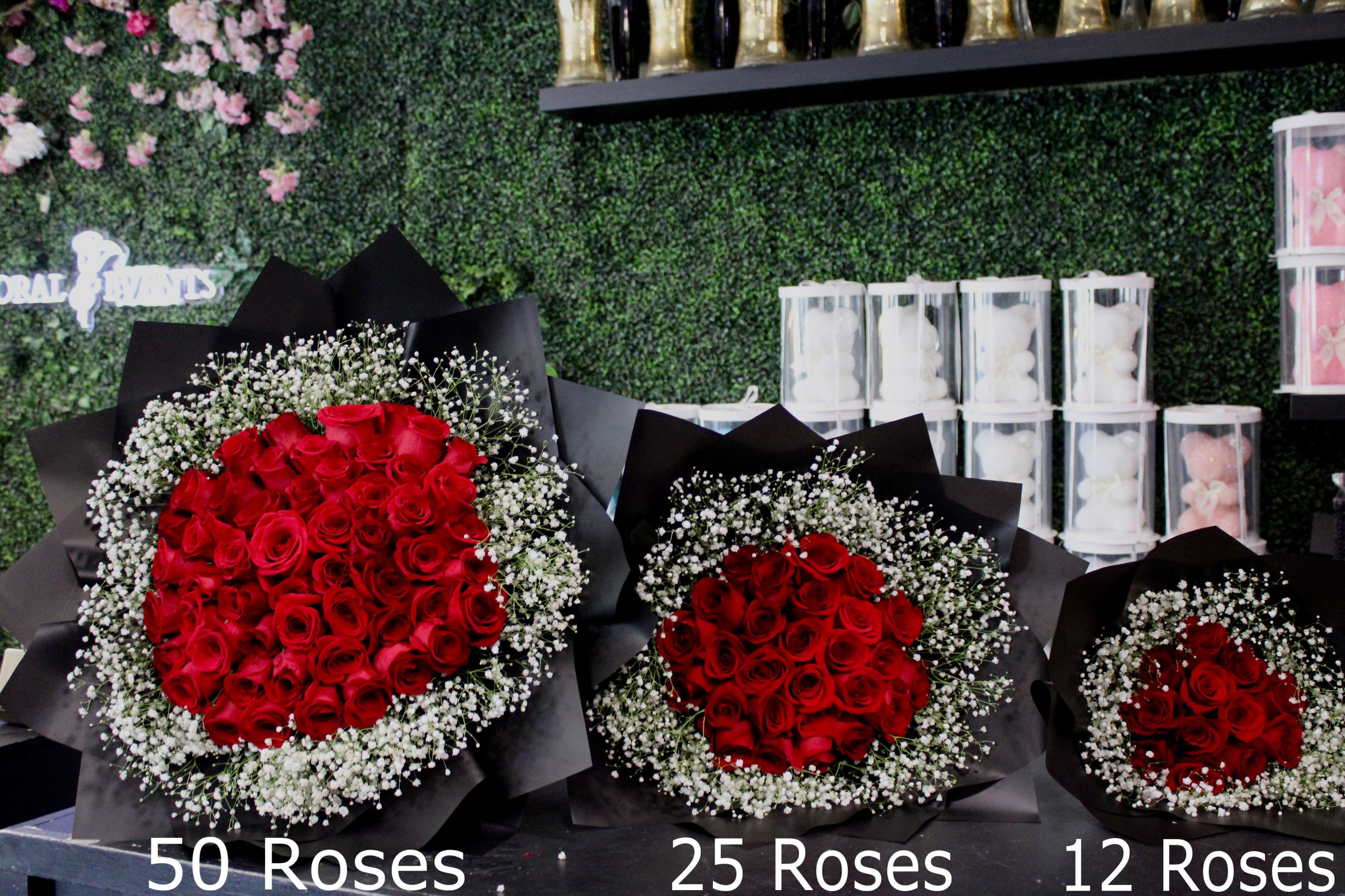Three bouquets of red roses with baby's breath in black wrap