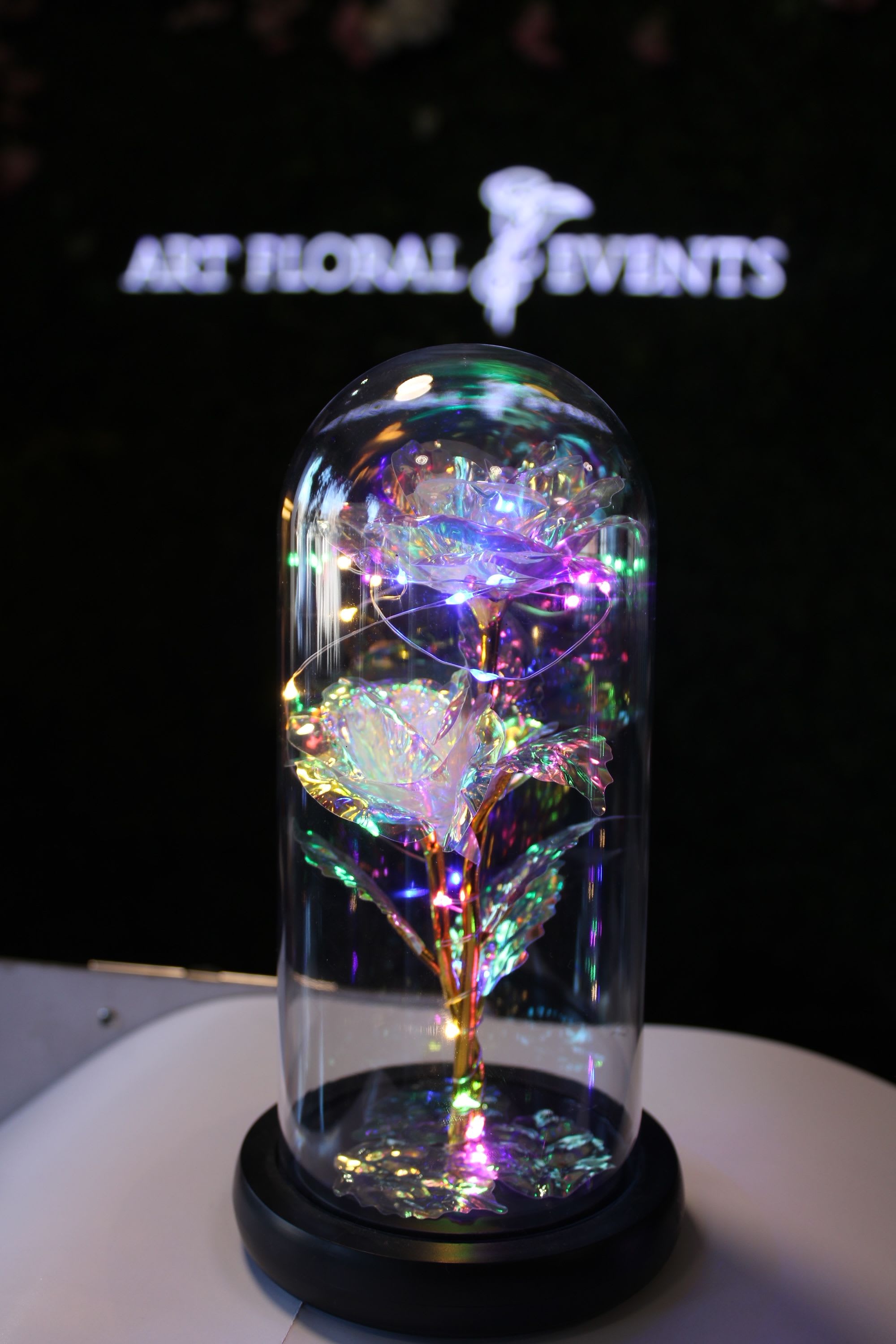 Iridescent decorative roses under a glass dome on a black base