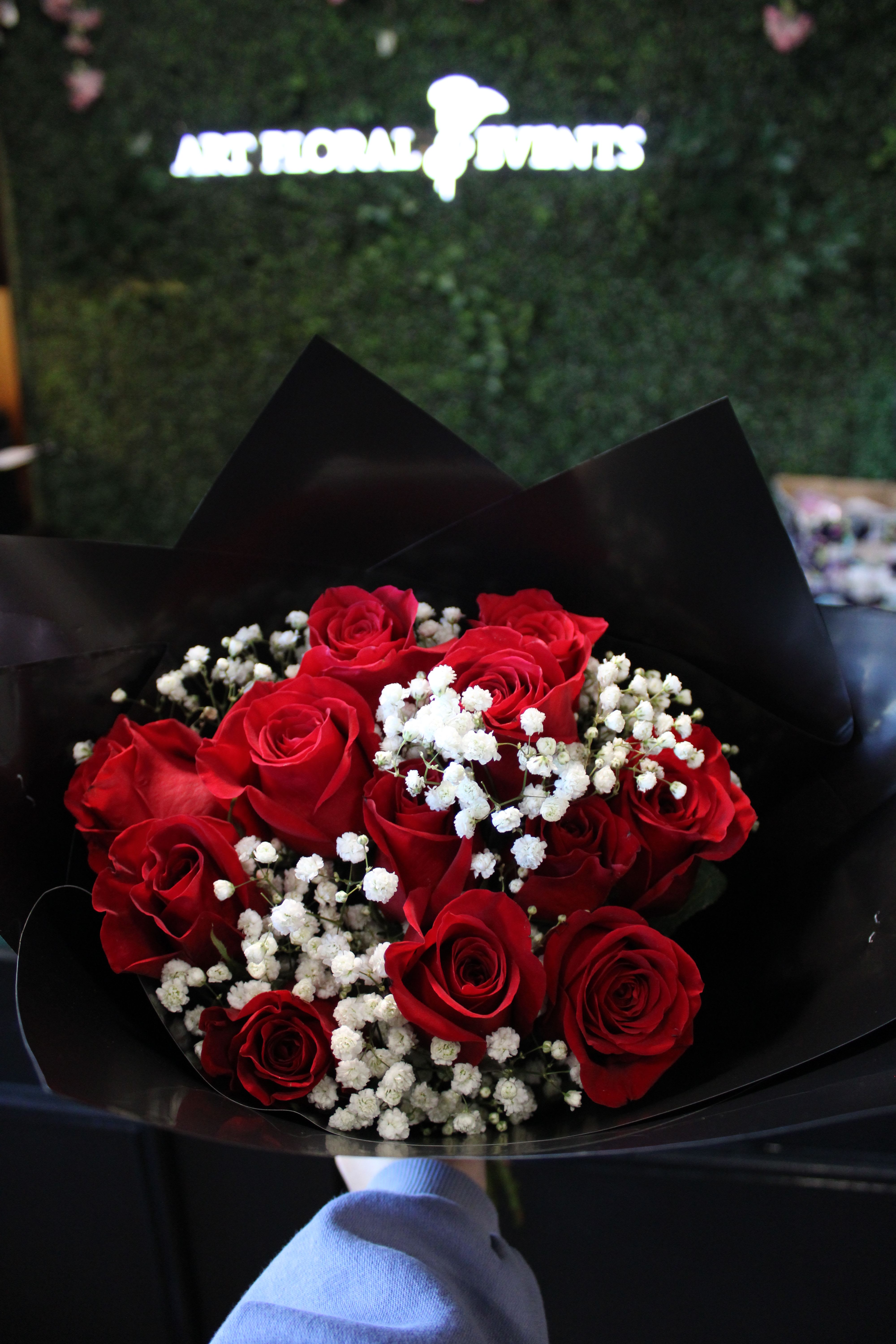 Bouquet of red roses with white baby's breath in black wrap