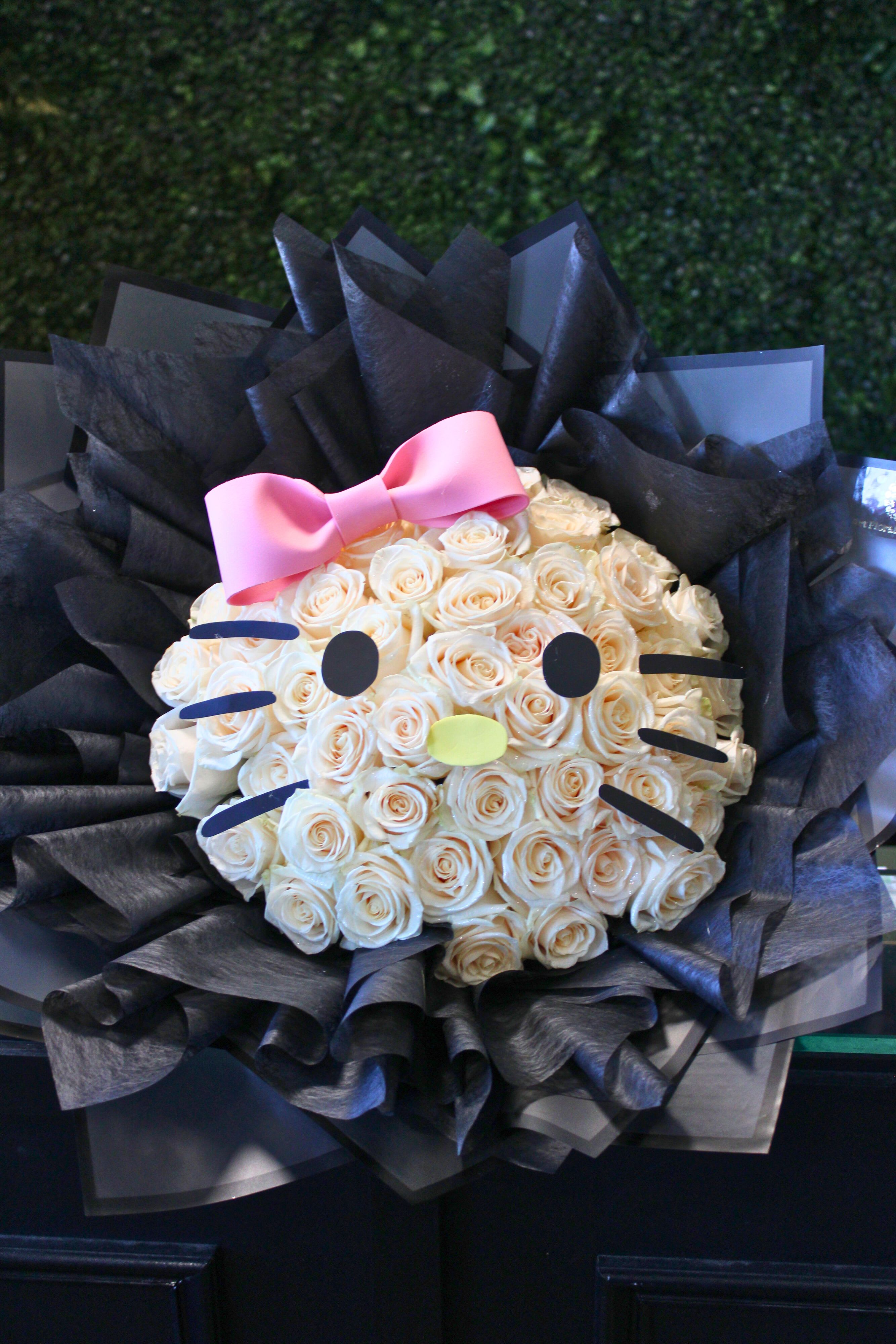 Bouquet of cream roses styled like a Hello Kitty face with a pink bow