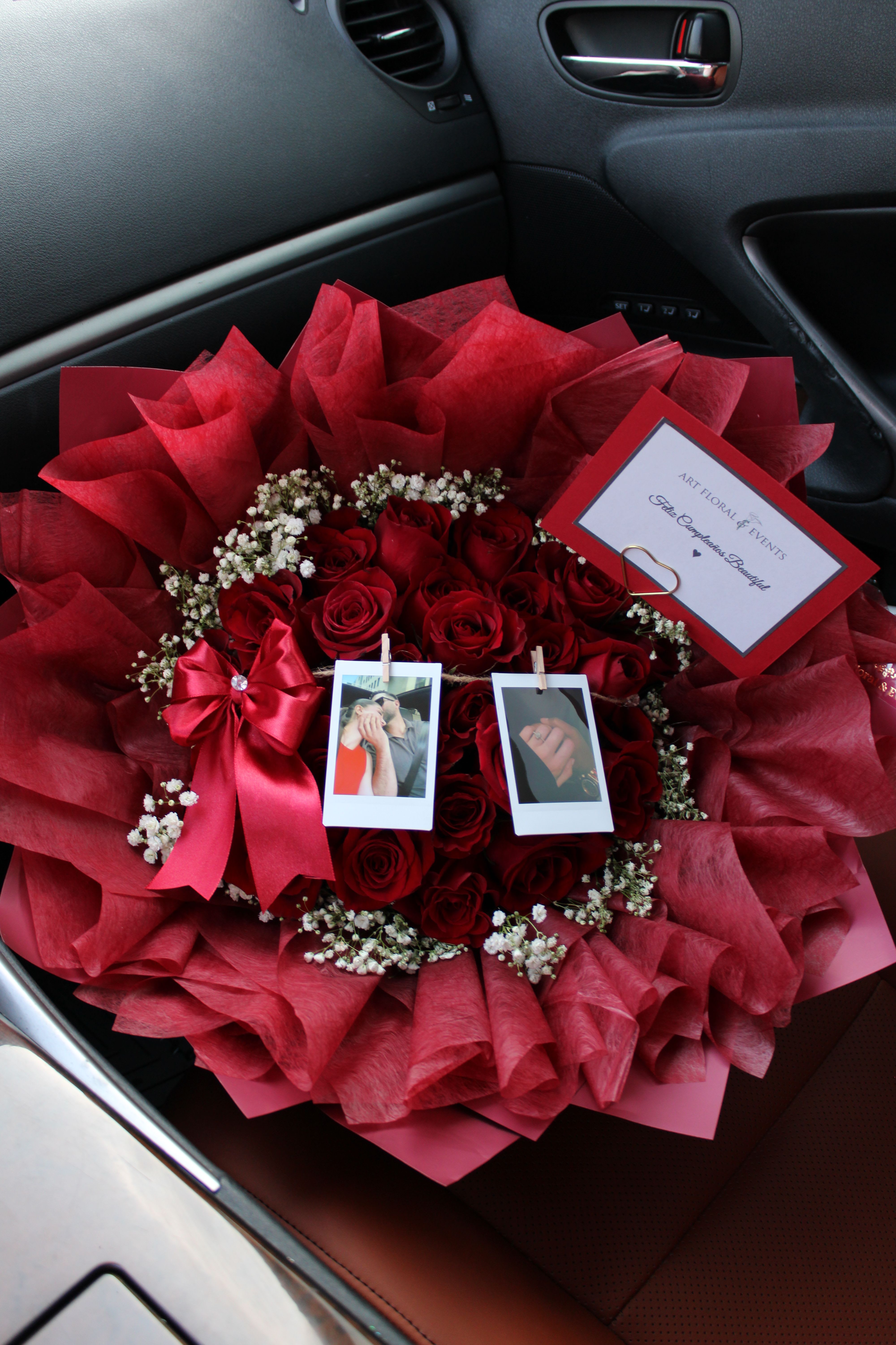 Bouquet of red roses with baby’s breath, ribbon, and photo clips in a car seat