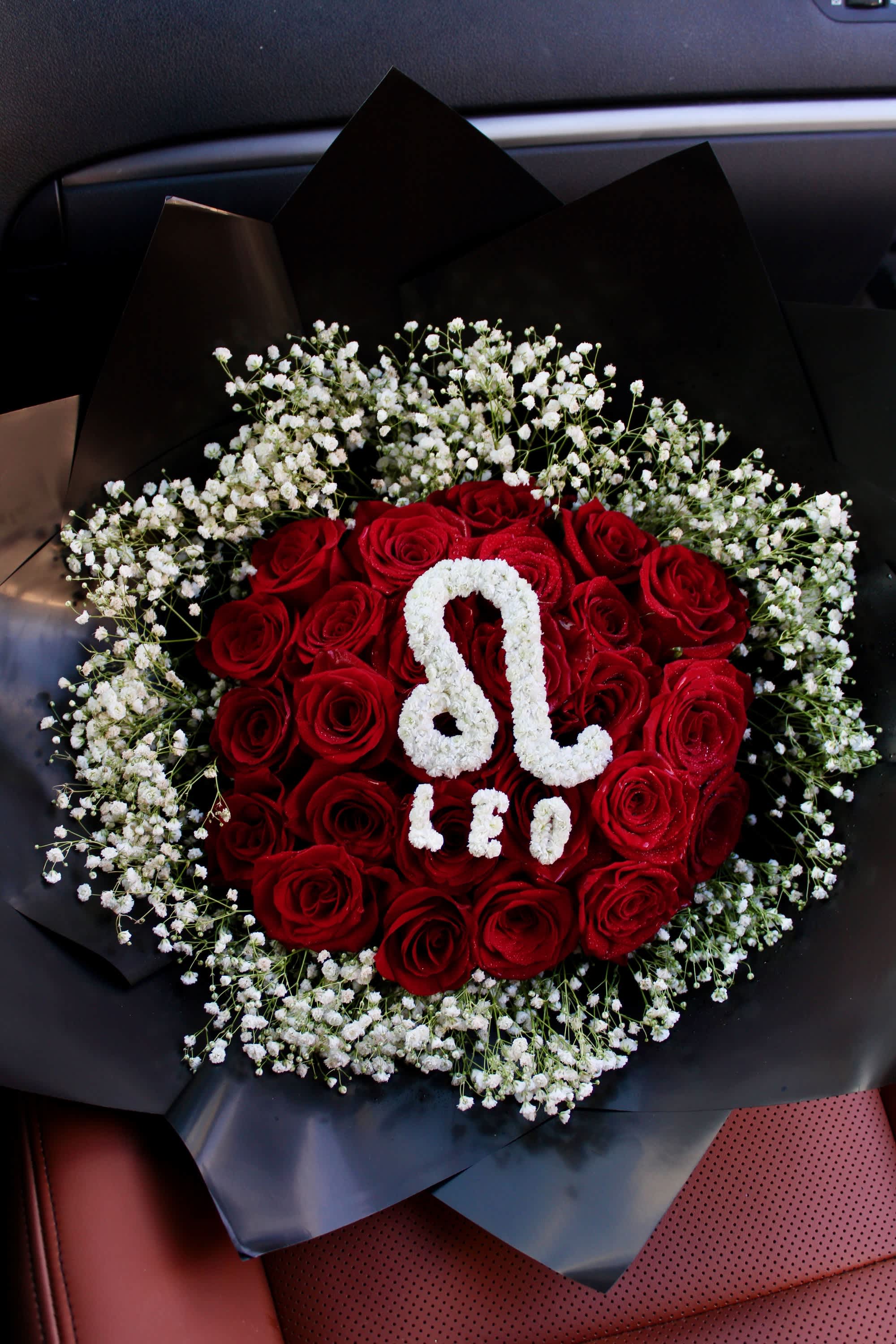 Red roses arranged with white baby's breath in black wrapping
