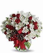 Red roses and white flowers in a glass vase with a red ribbon
