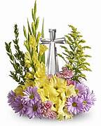 Standing floral spray with yellow and purple flowers and a silver ribbon cross