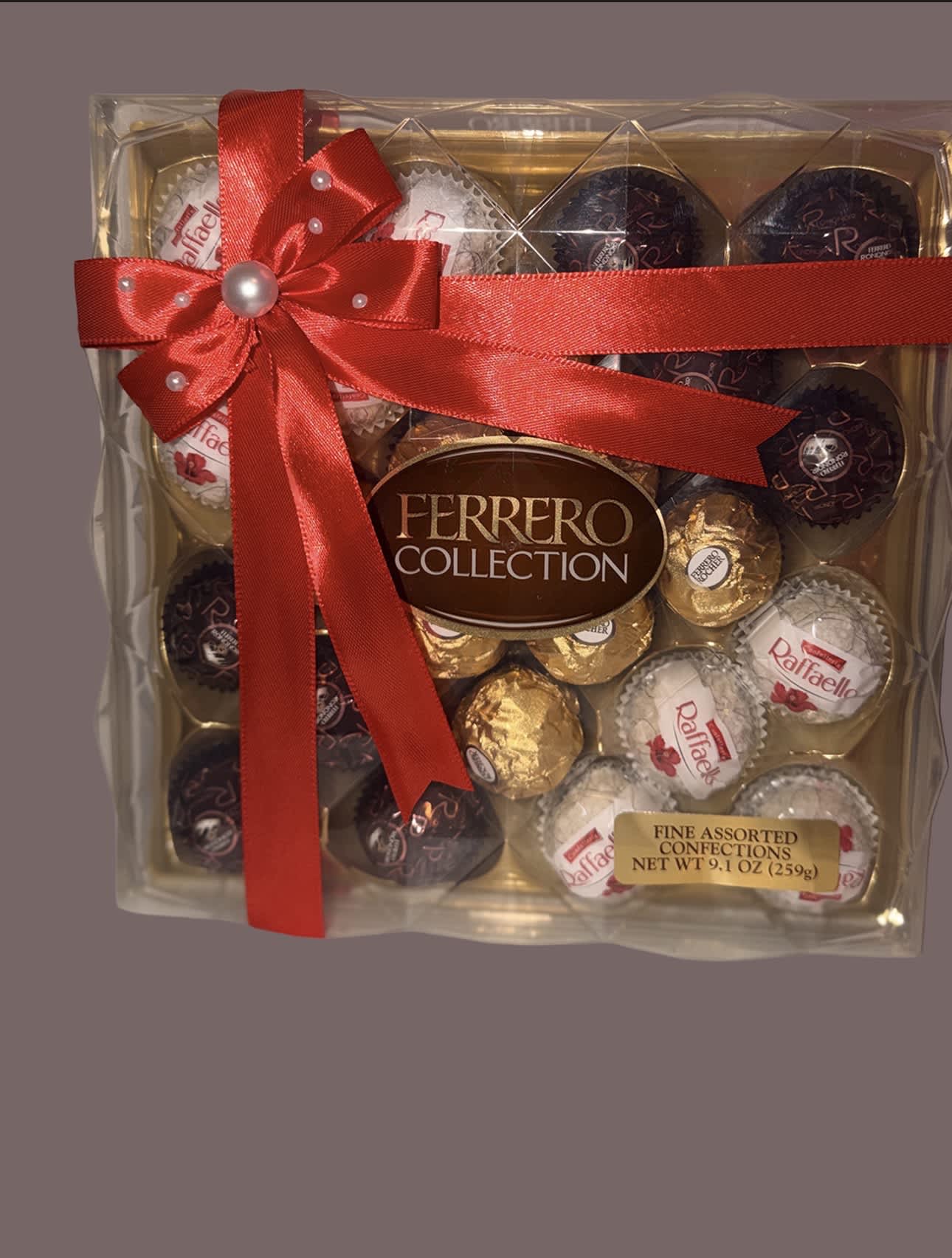 Assorted Ferrero Rocher and Raffaello chocolates in a clear gift box with a red ribbon