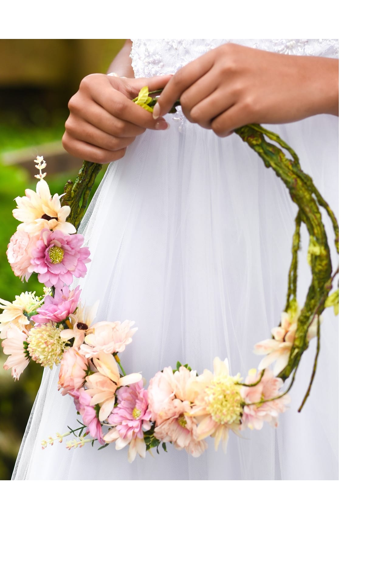 Person holding a floral wreath with pink and cream flowers