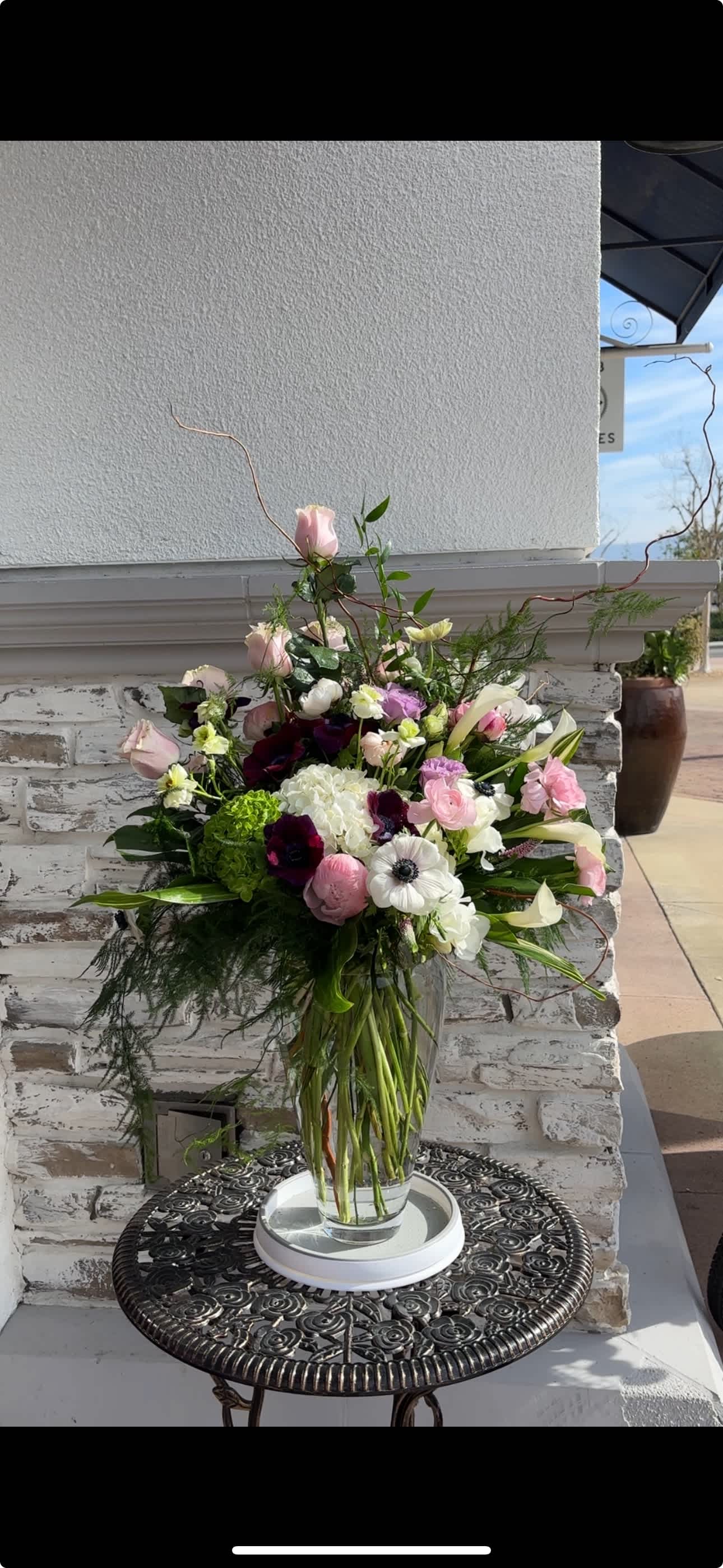 Tall mixed bouquet in a clear glass vase with pink, white, and purple blooms
