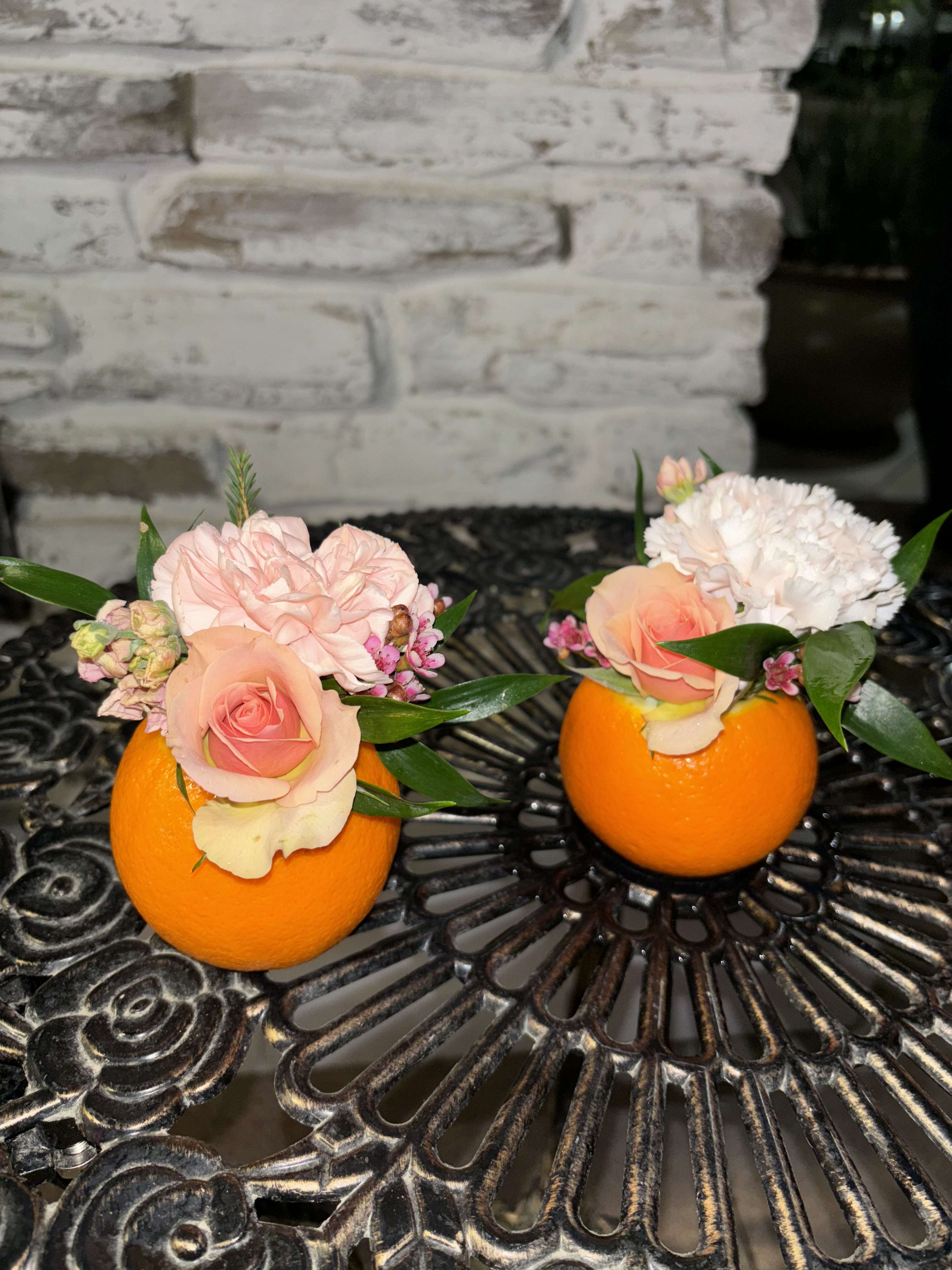 Two small floral arrangements in orange halves on a table