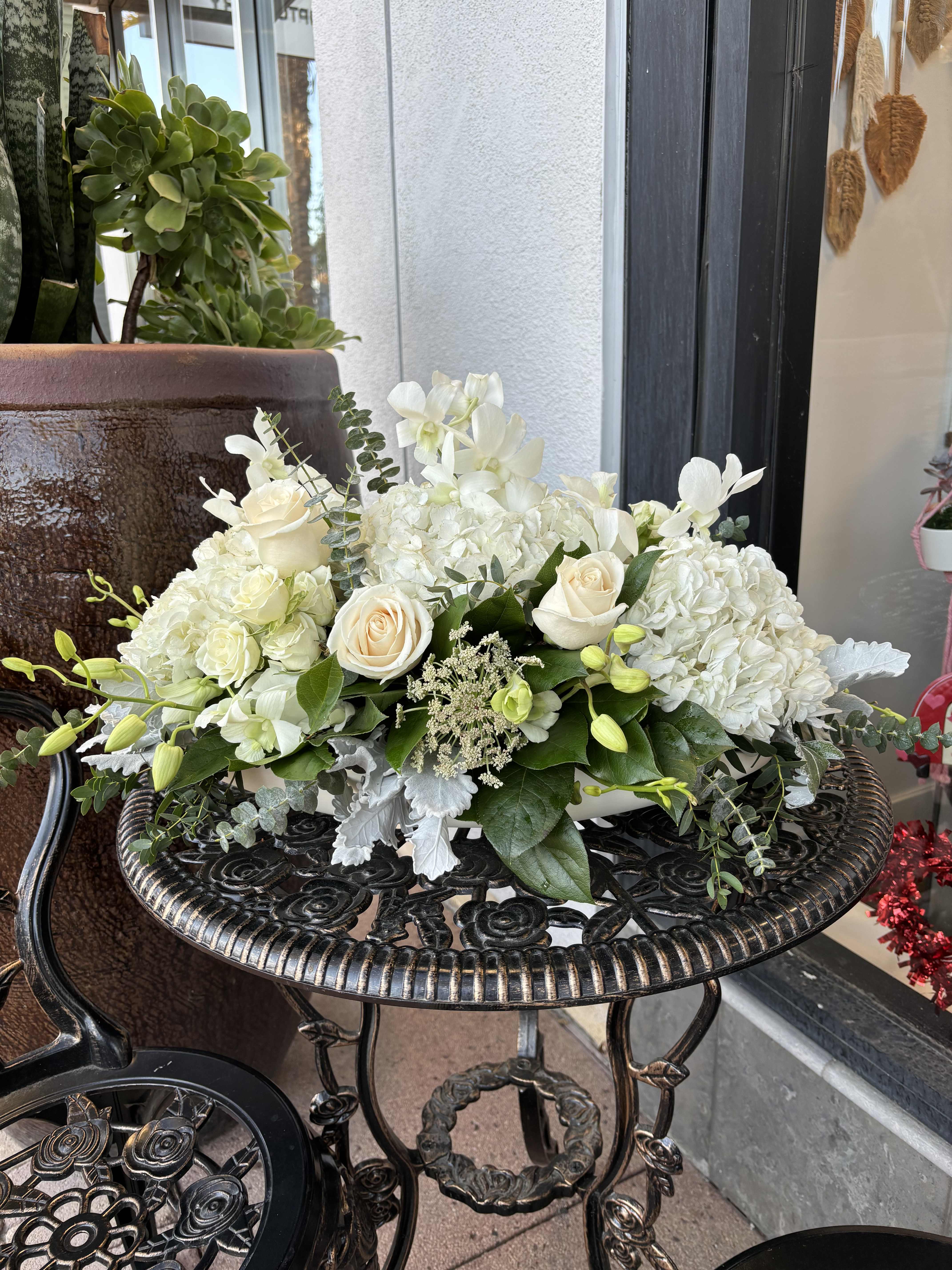 White floral arrangement with roses and hydrangeas in a low container