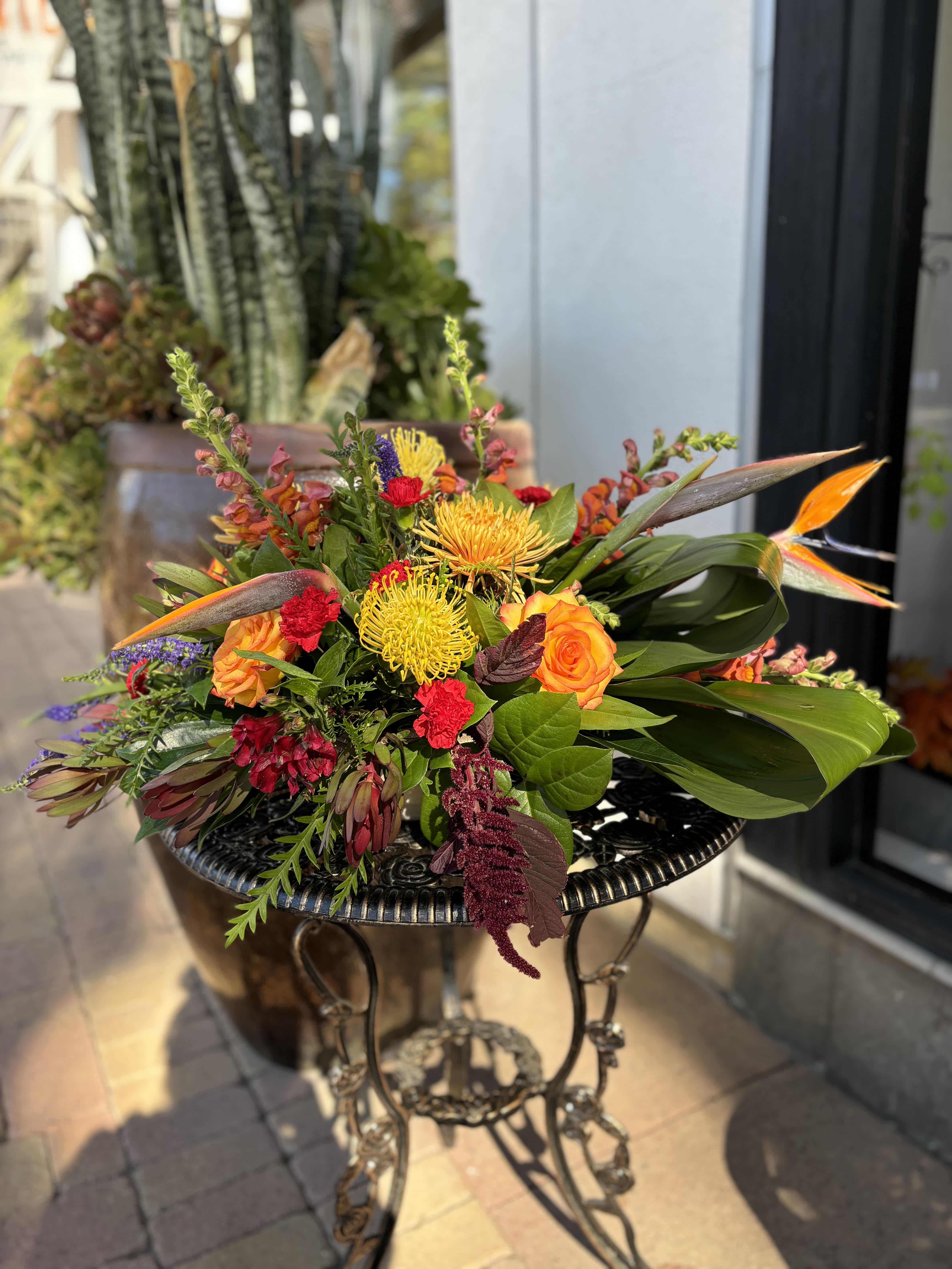 Colorful mixed bouquet with orange roses and yellow blooms on a metal table