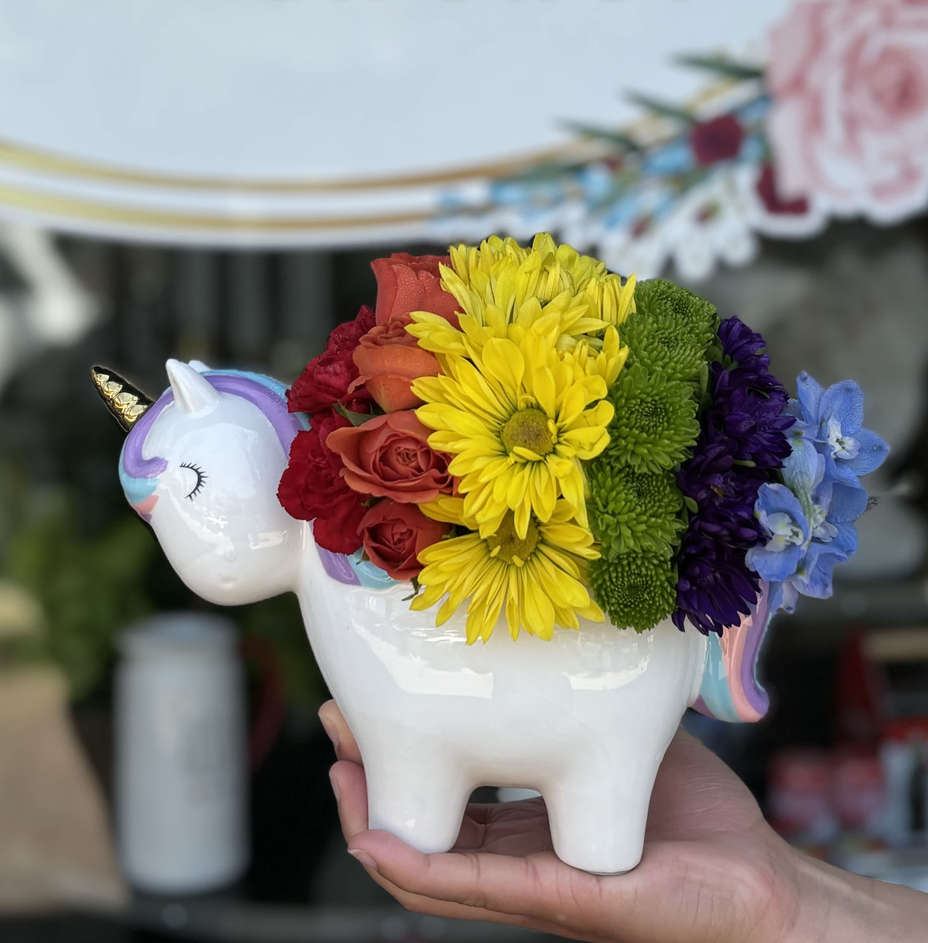 Rainbow flower arrangement in a unicorn-shaped ceramic container