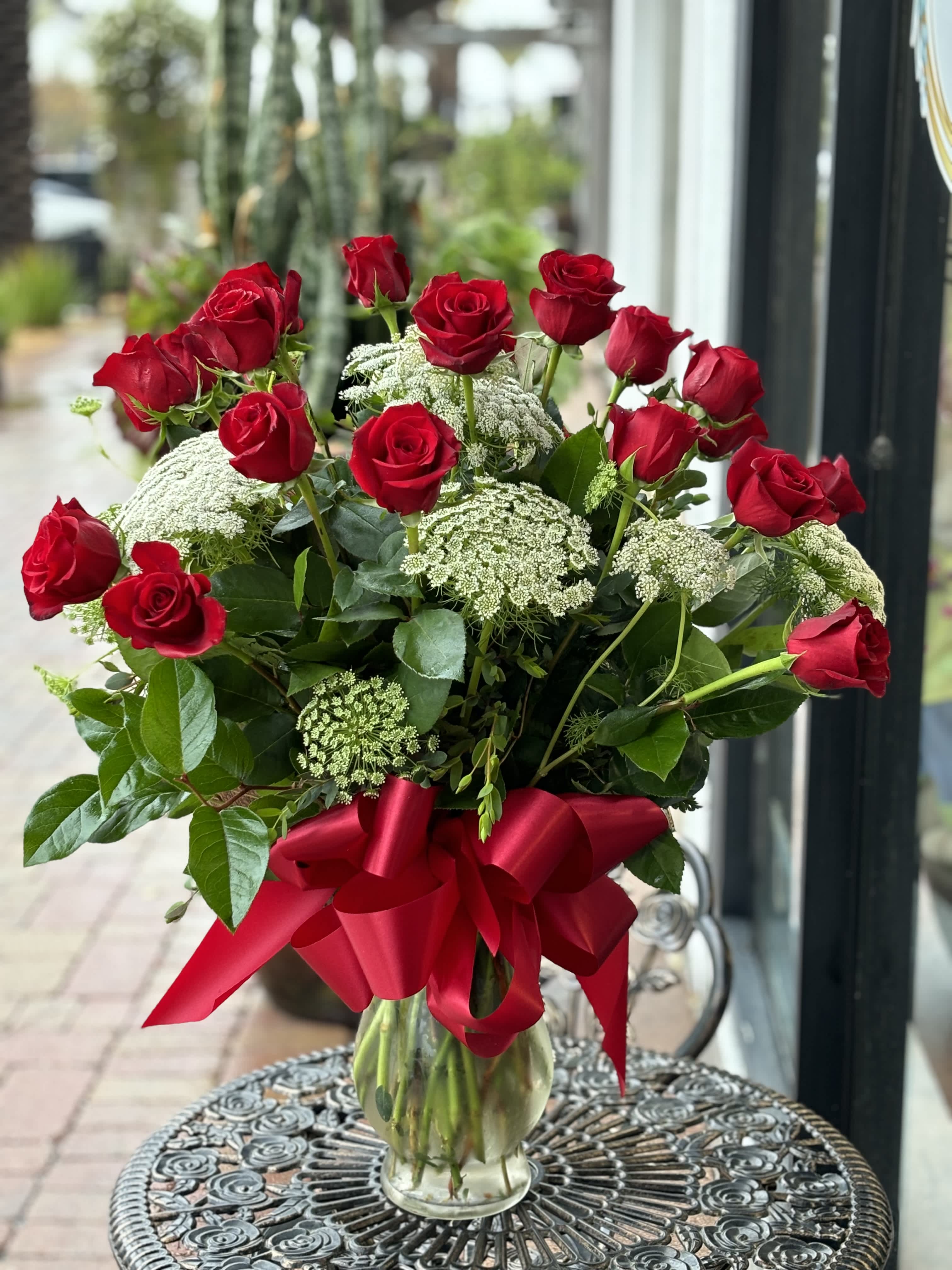 Red roses in a clear glass vase with a red ribbon bow
