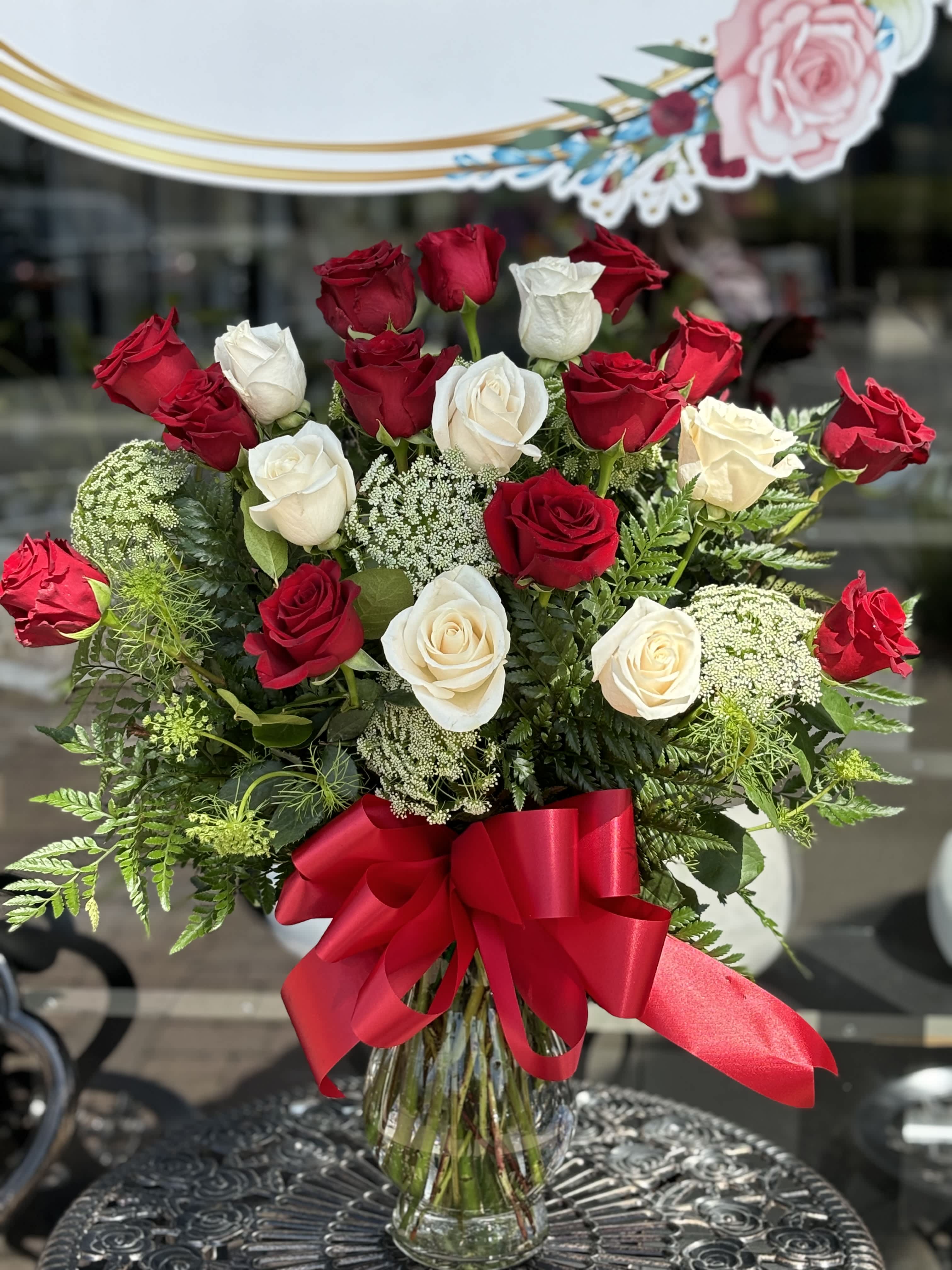 Red and white roses in a glass vase with a red ribbon