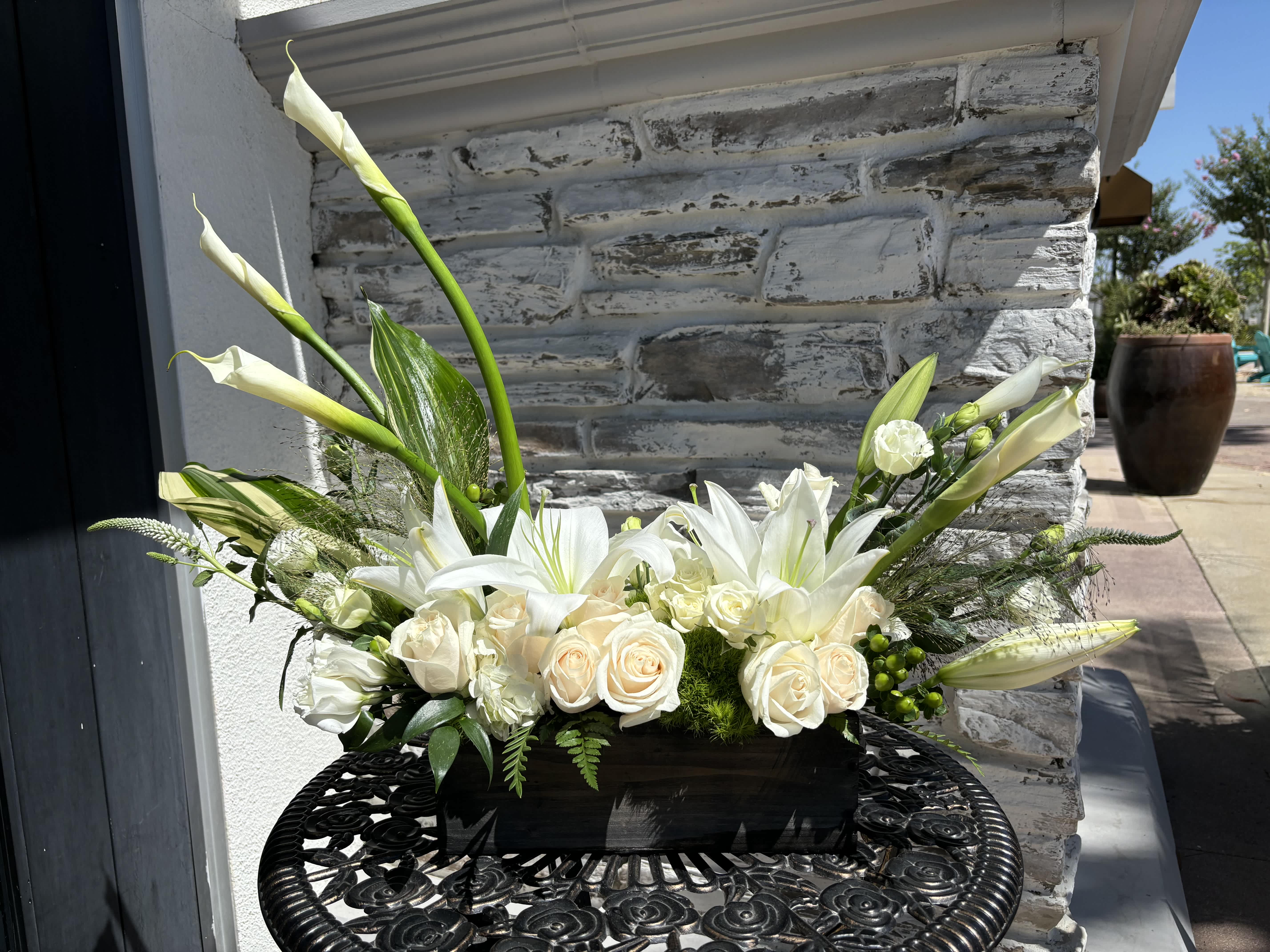 White roses and lilies in a black rectangular container