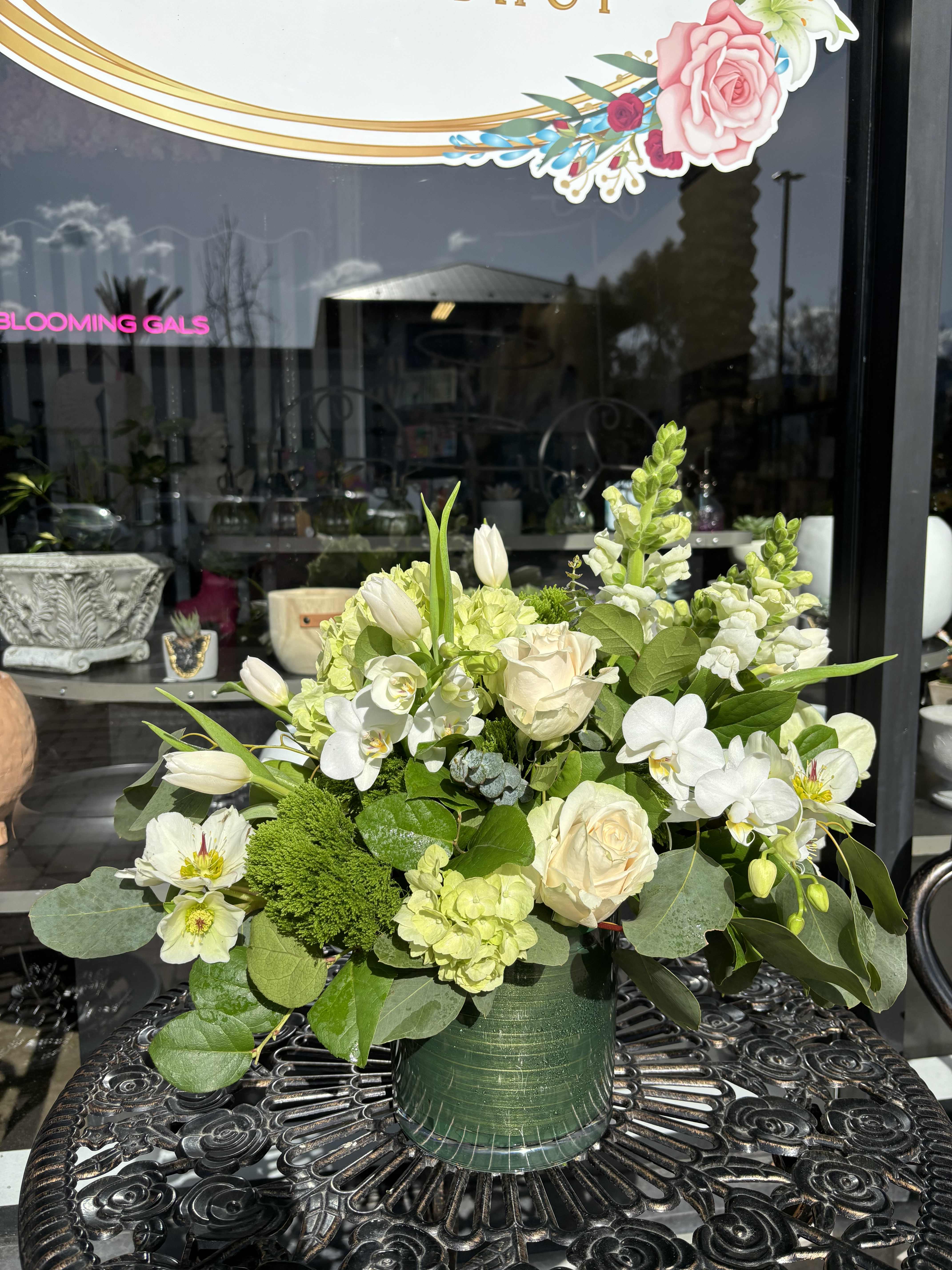 White and pale green floral arrangement in a green vase