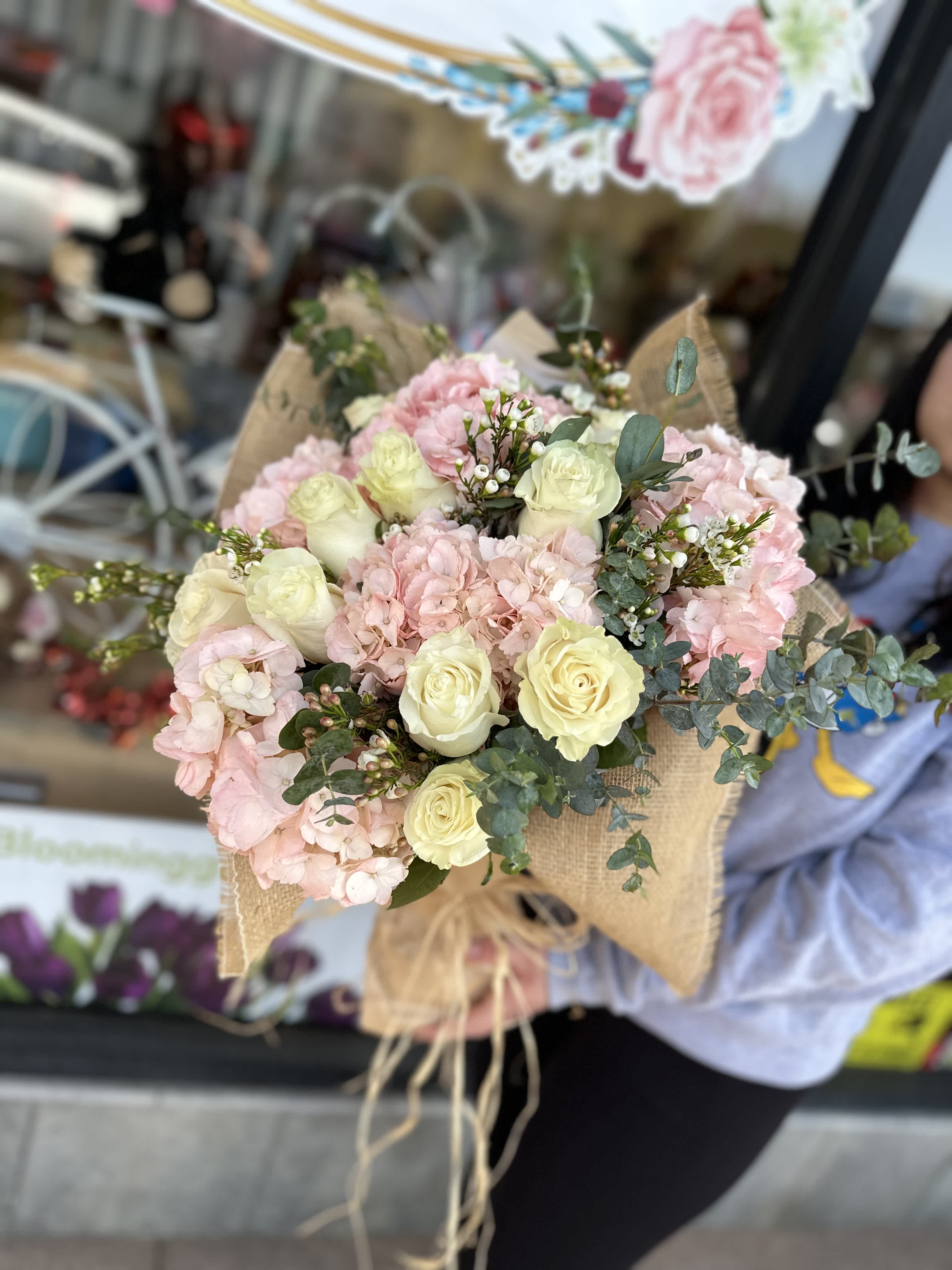 Bouquet of pale pink hydrangeas and cream roses wrapped in burlap