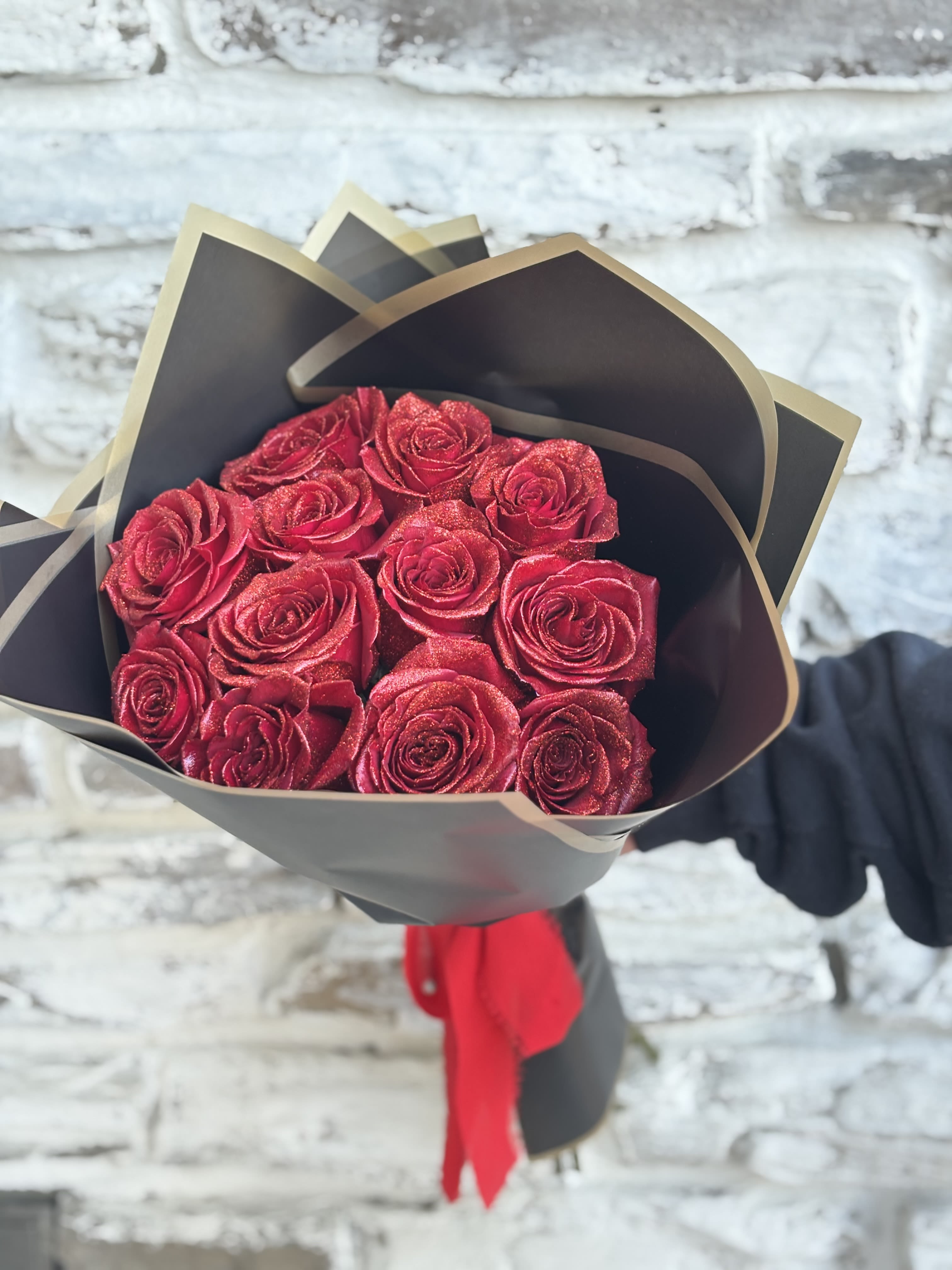 Bouquet of red roses wrapped in black paper with a red ribbon