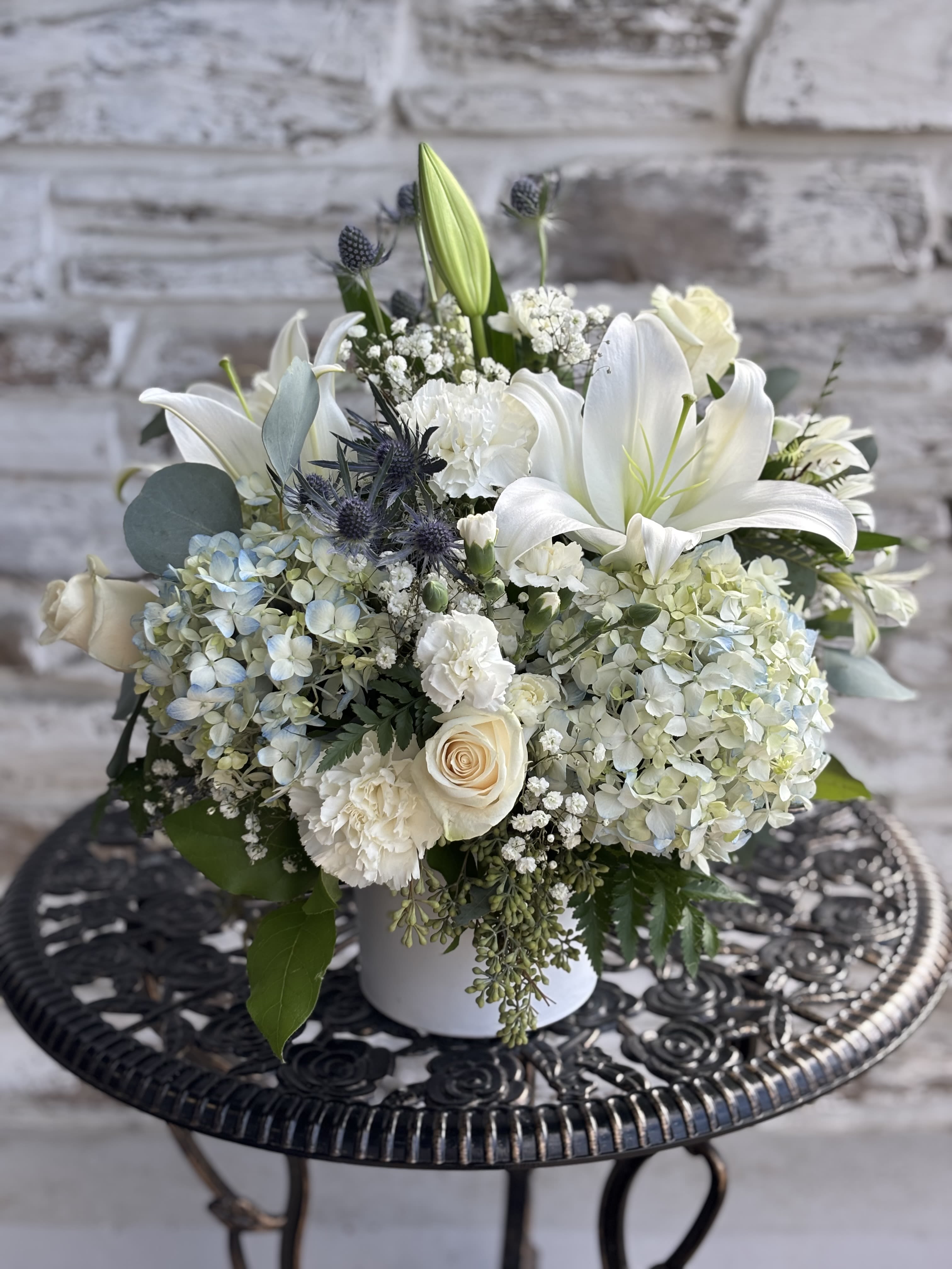 White lilies and hydrangeas arranged in a white vase