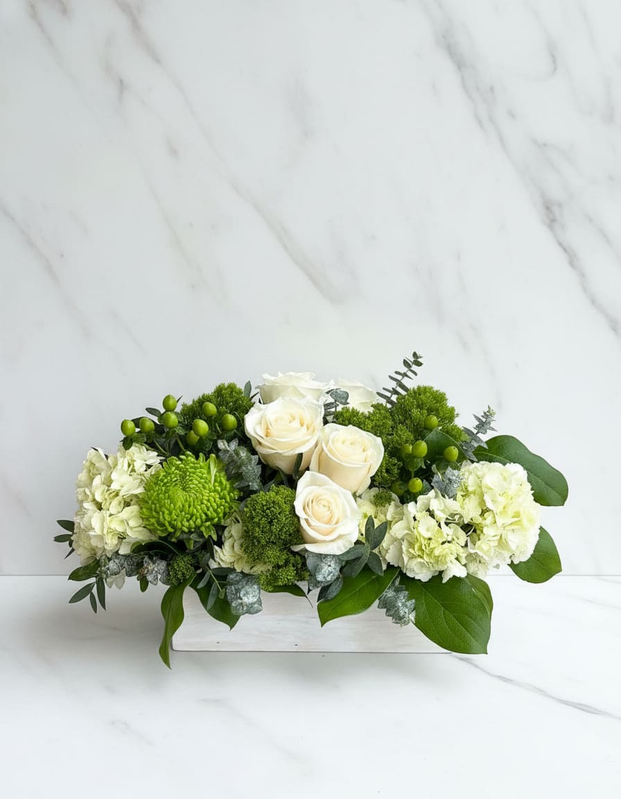 The Hamptons  - This crisp mix of white and green arrangement includes roses and hydrangeas. The Hamptons is the perfect gift for a Grandparents Day, Sympathy, Earth Day, or just because. It's size and shape also make it a fitting centerpiece for any table.   APPROXIMATE DIMENSIONS 18" W X 10" H