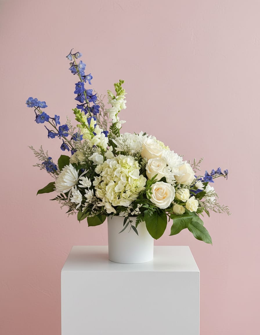 White roses and hydrangea in a white vase with blue flowers