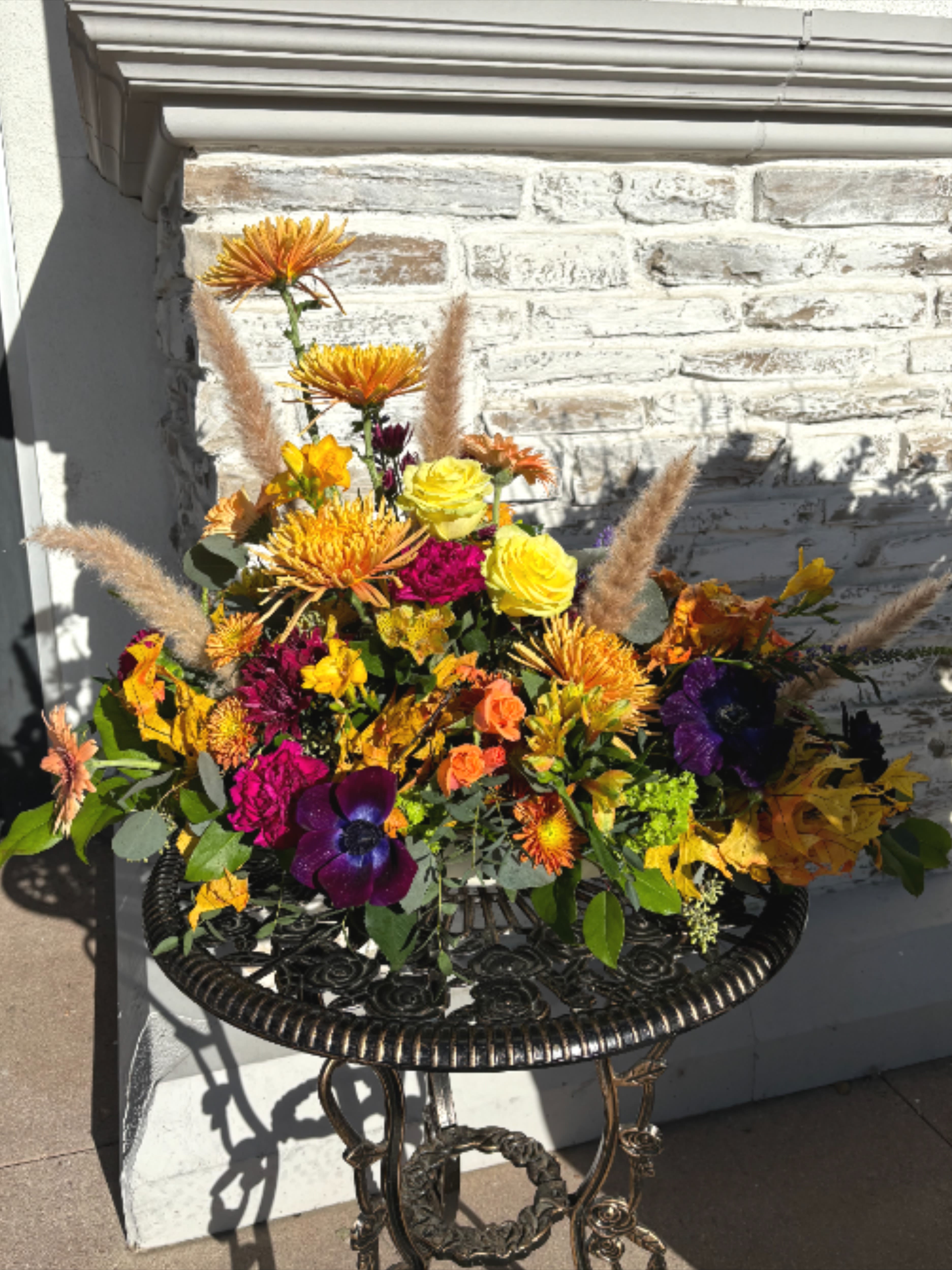 Colorful floral arrangement with yellow roses and orange blooms in a black metal table