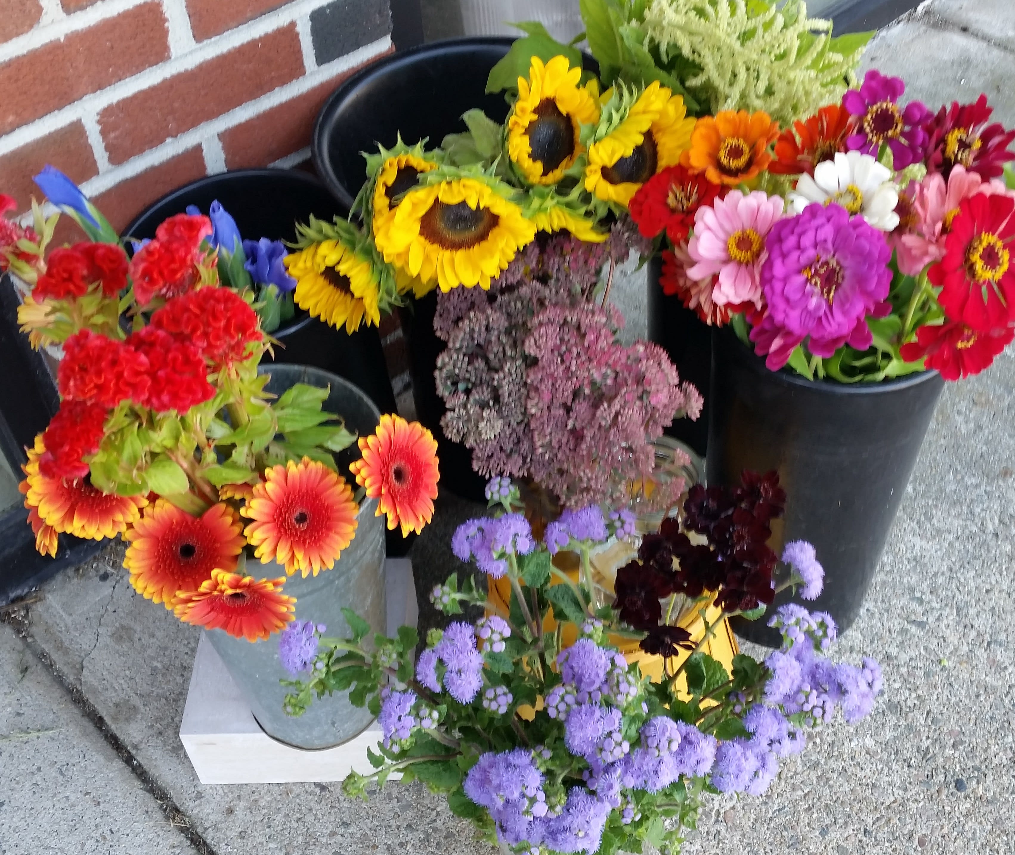 Assorted colorful flower buckets with sunflowers, gerbera daisies, and purple blooms