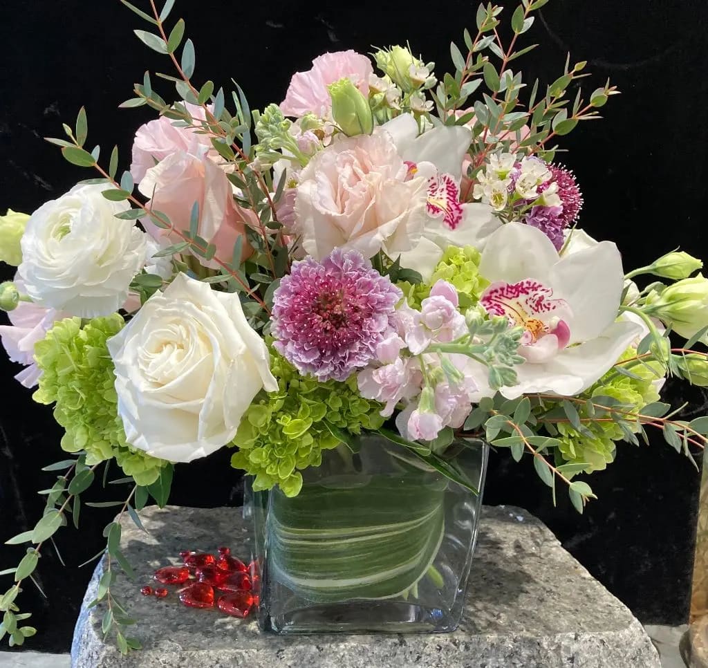 Mixed bouquet of white, pink, and green flowers in a clear glass vase