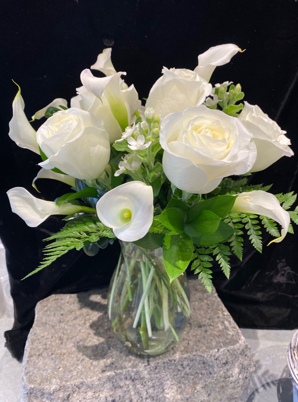 White roses and calla lilies in a clear glass vase